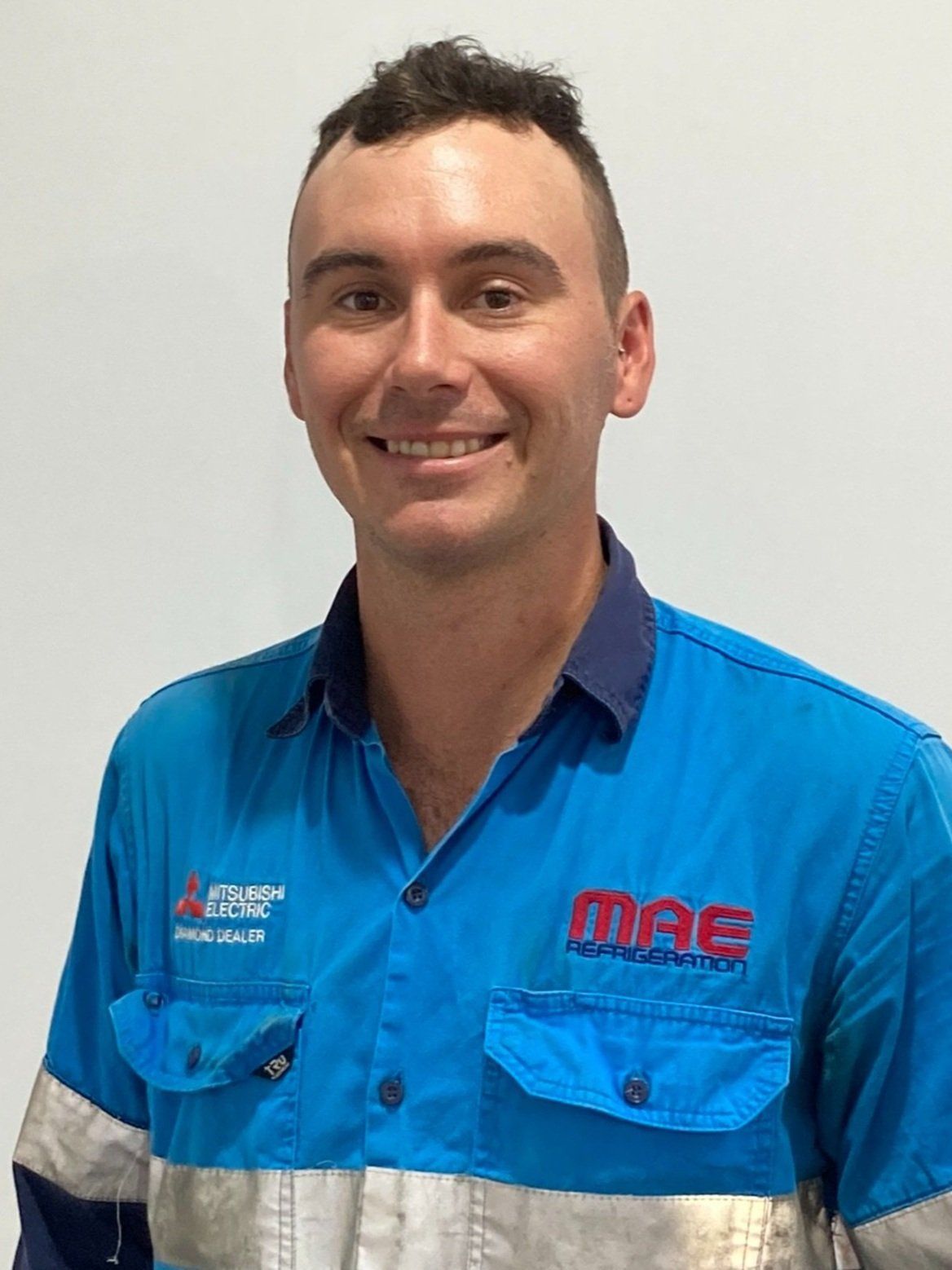 Man in blue work shirt smiling, logo 