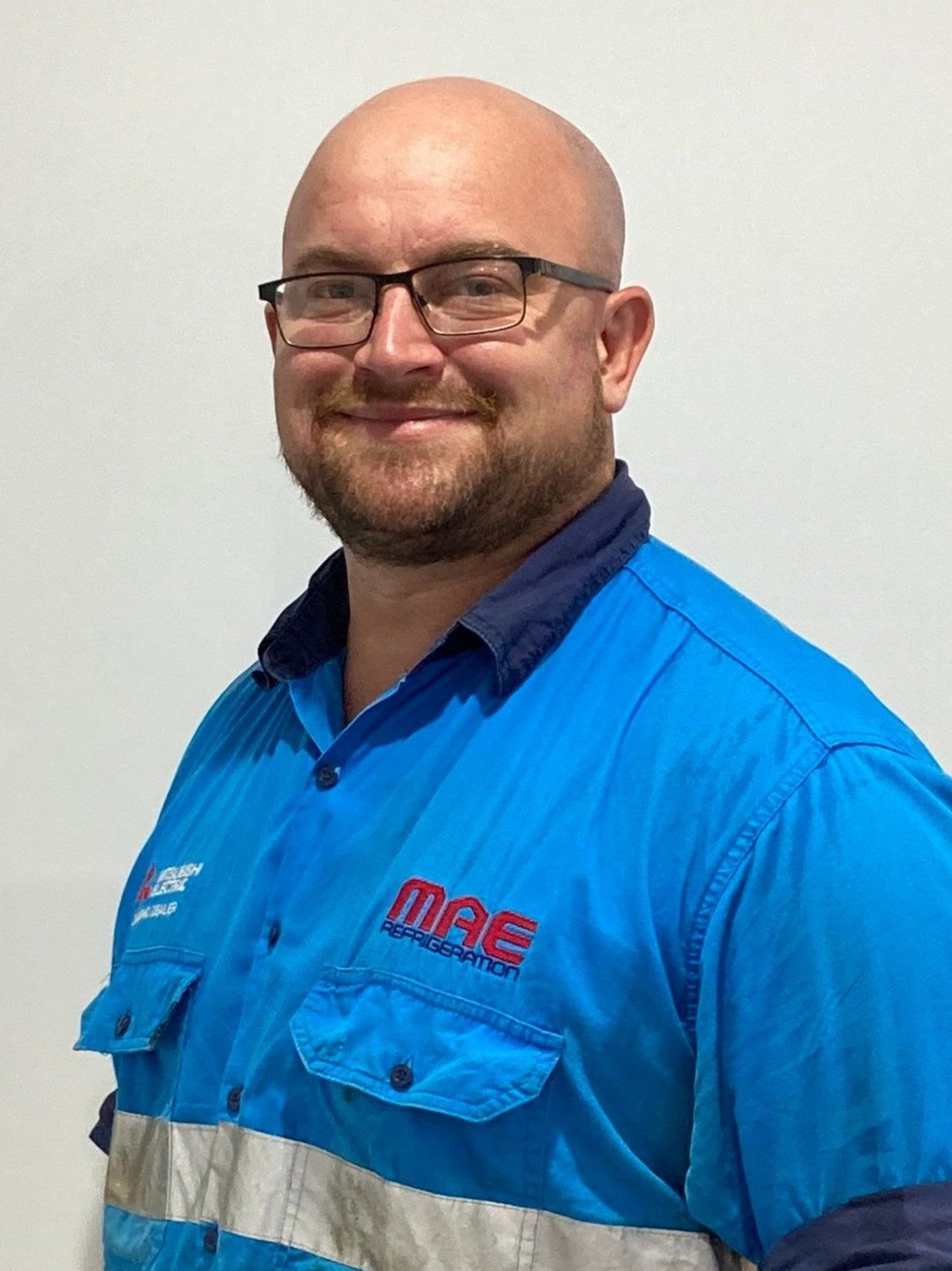 Man with glasses and bald head in a blue work shirt — MAE Refrigeration In Portsmith, QLD