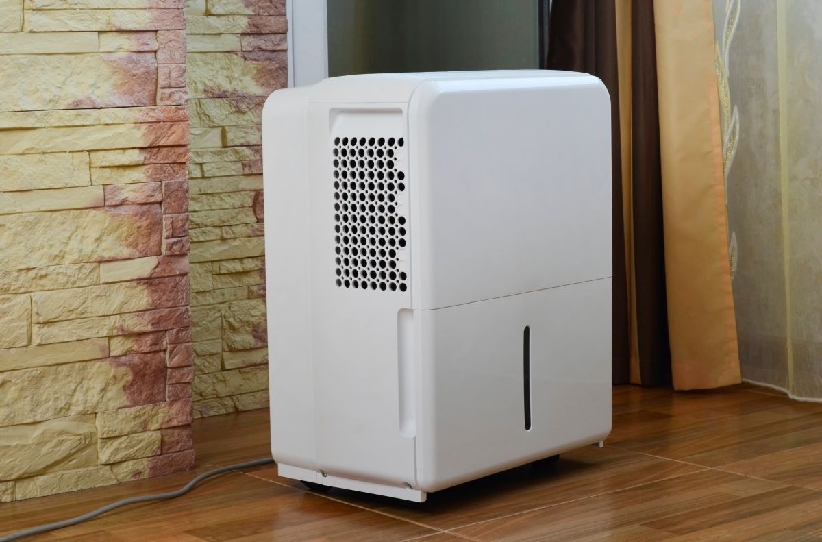 White Dehumidifier on A Wooden Floor, Near a Stone Wall — MAE Refrigeration In Innisfail, QLD
