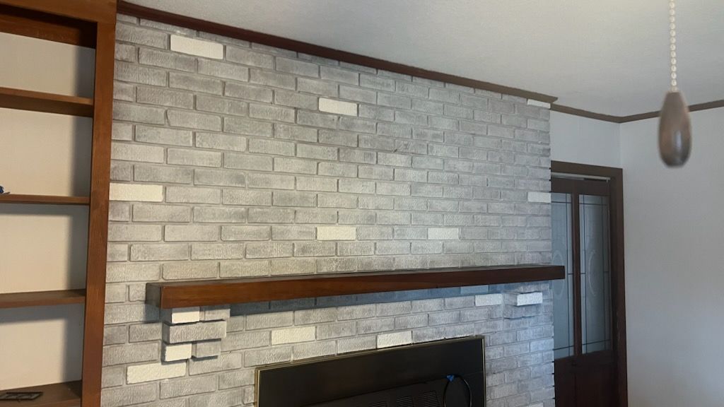 Brick fireplace with dark wood mantel, built-in bookshelf, and white and gray brick facade.