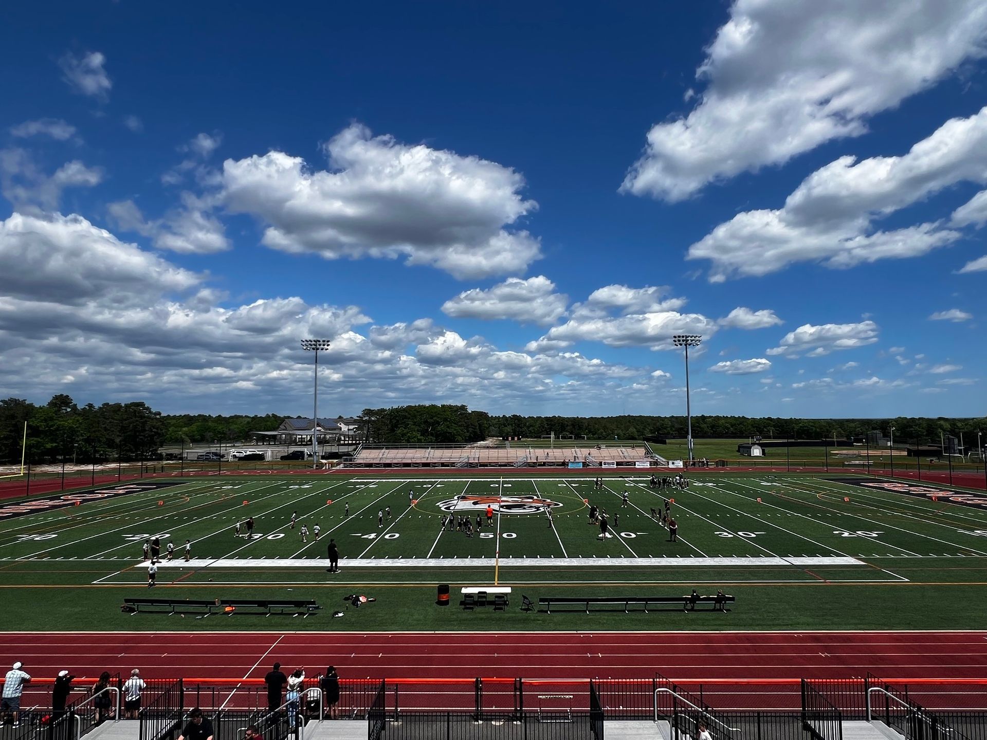 Football player in maroon jersey holding ball, smiling, surrounded by teammates on a field.