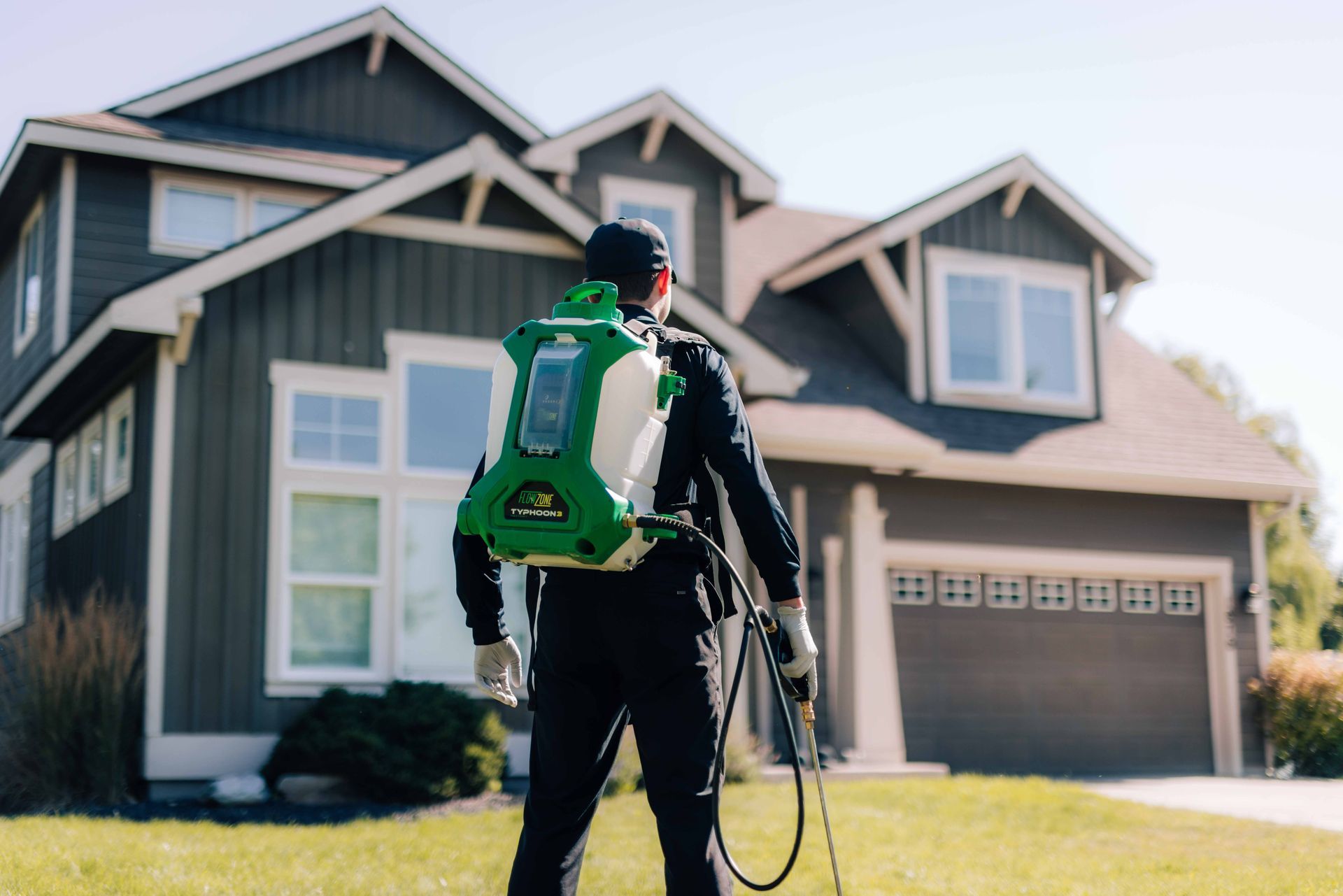 A man with a green backpack is standing in front of a house.