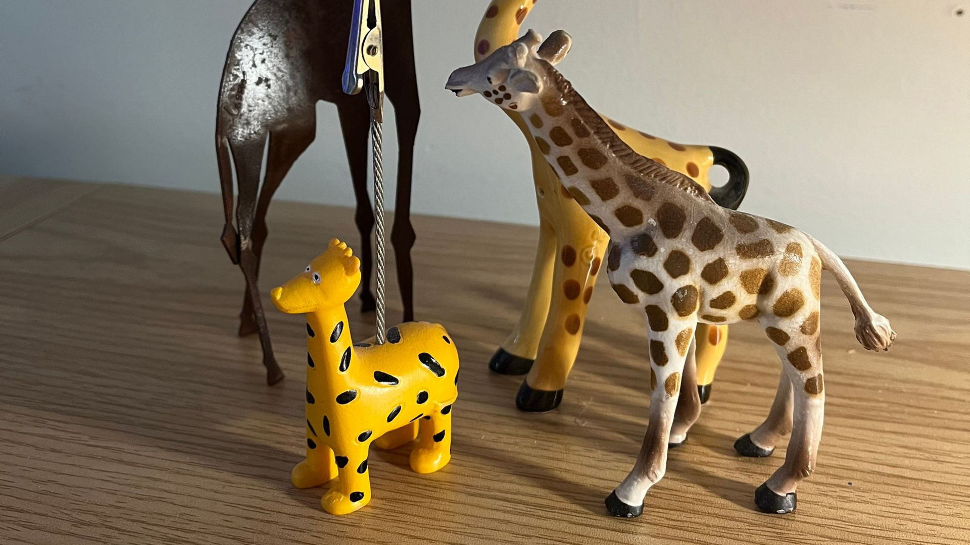 A collection of four plastic giraffe figurines of different sizes and designs on a wooden surface.