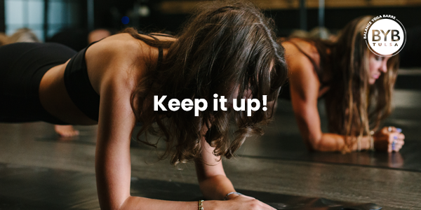 Two people holding a forearm plank on yoga mats in a dark studio with the text 