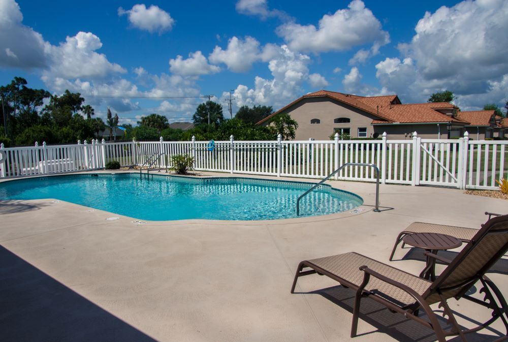 A Large Swimming Pool Surrounded by Chairs and a White Fence — Aztech Fencing In Taree, NSW