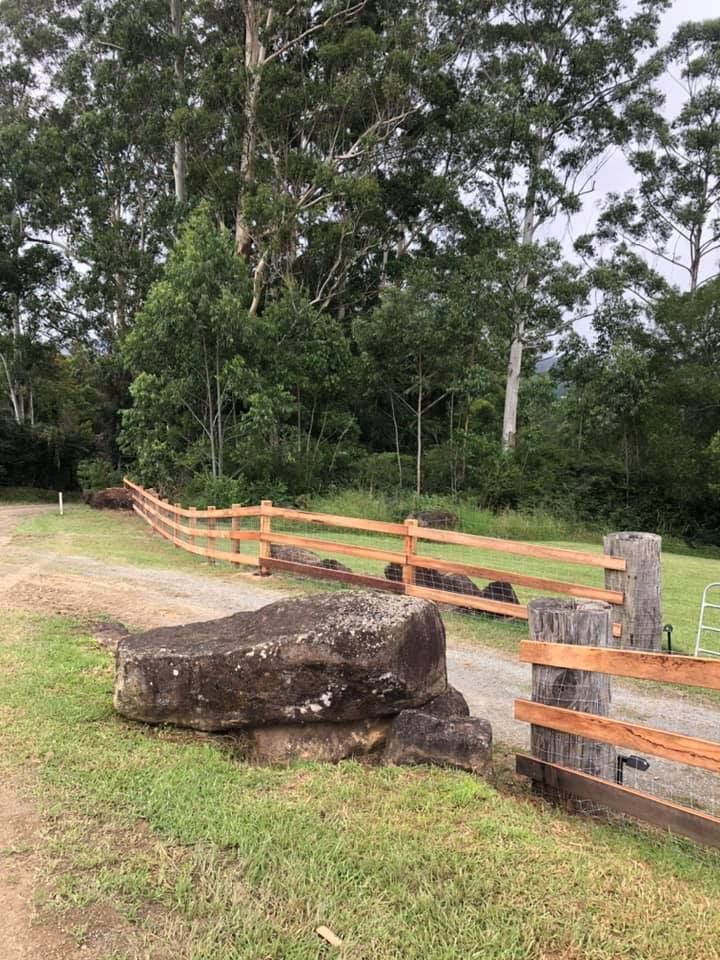 A Wooden Fence Surrounds a Grassy Field With Trees in the Background — Aztech Fencing In North Haven, NSW