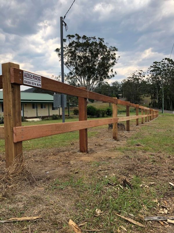 A Wooden Fence is Sitting in the Middle of a Grassy Field — Aztech Fencing In Bonny Hills, NSW