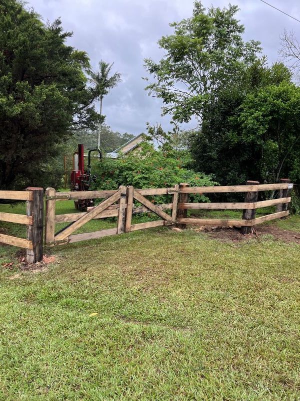 A Wooden Fence is in the Middle of a Grassy Field — Aztech Fencing In Laurieton, NSW