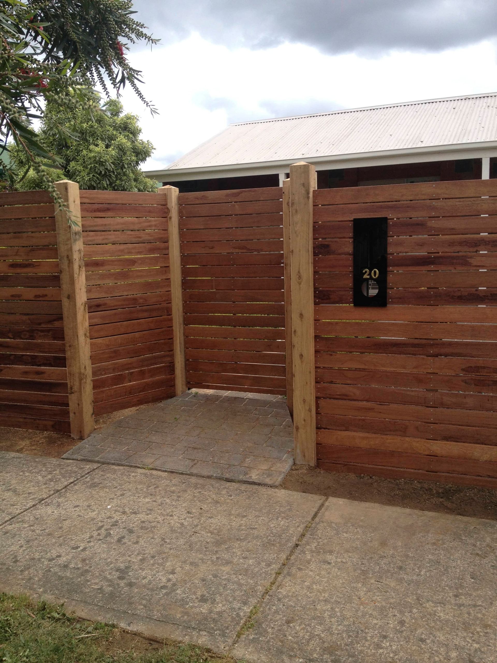 A wooden fence surrounds a driveway leading to a house — Aztech Fencing In Upsalls Creek, NSW