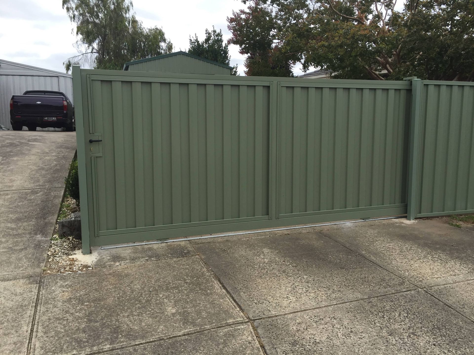 A green fence with a black car parked behind it — Aztech Fencing In Upsalls Creek, NSW
