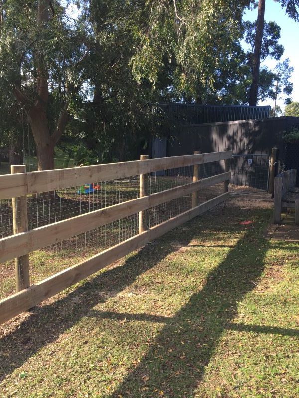 A Wooden Fence Surrounds a Grassy Area — Aztech Fencing In Lake Cathie, NSW