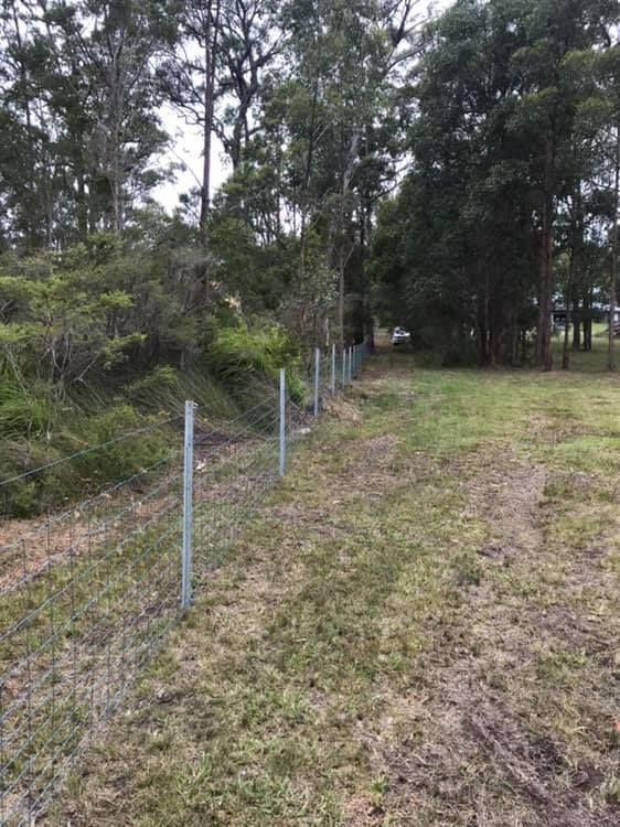 A Fence Surrounds a Grassy Field With Trees in the Background — Aztech Fencing In Harrington, NSW