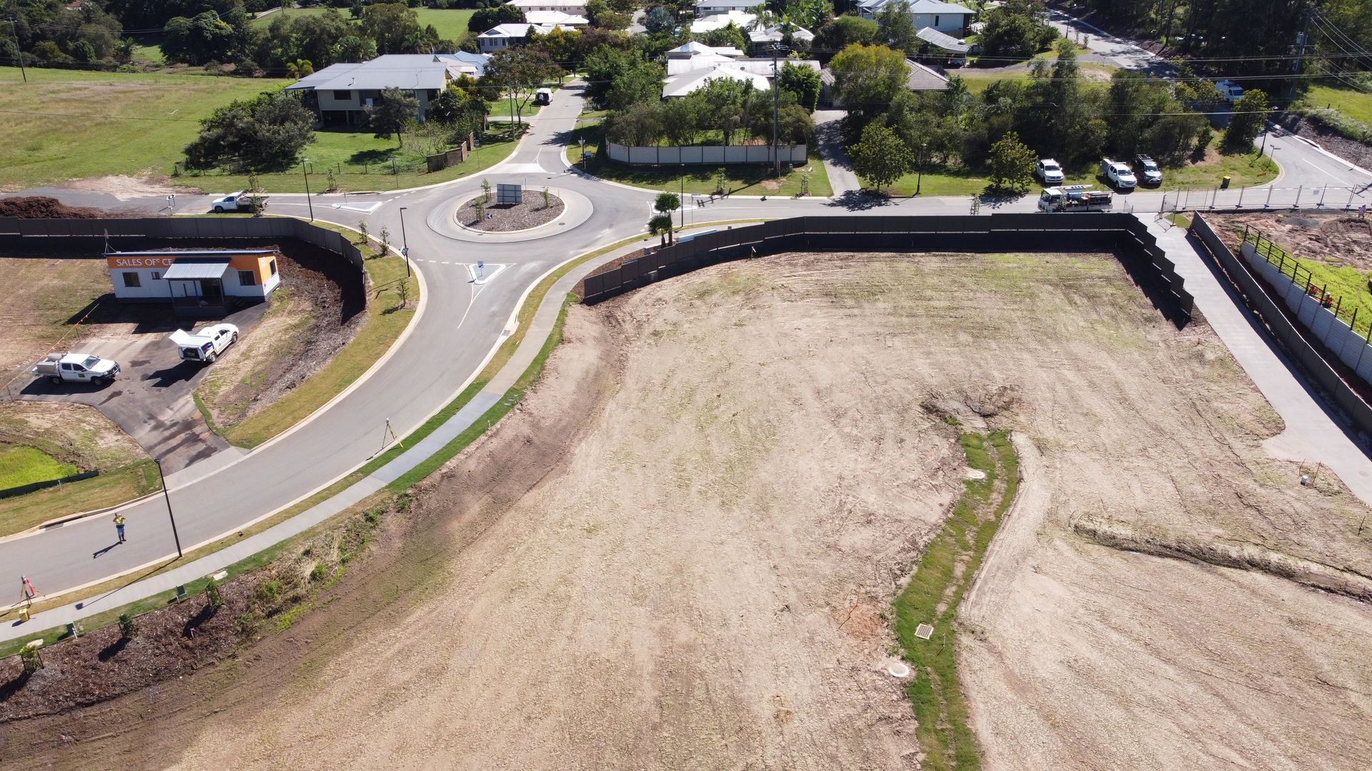 Aerial view of a suburban neighborhood with rows of houses, green lawns, and curving streets.