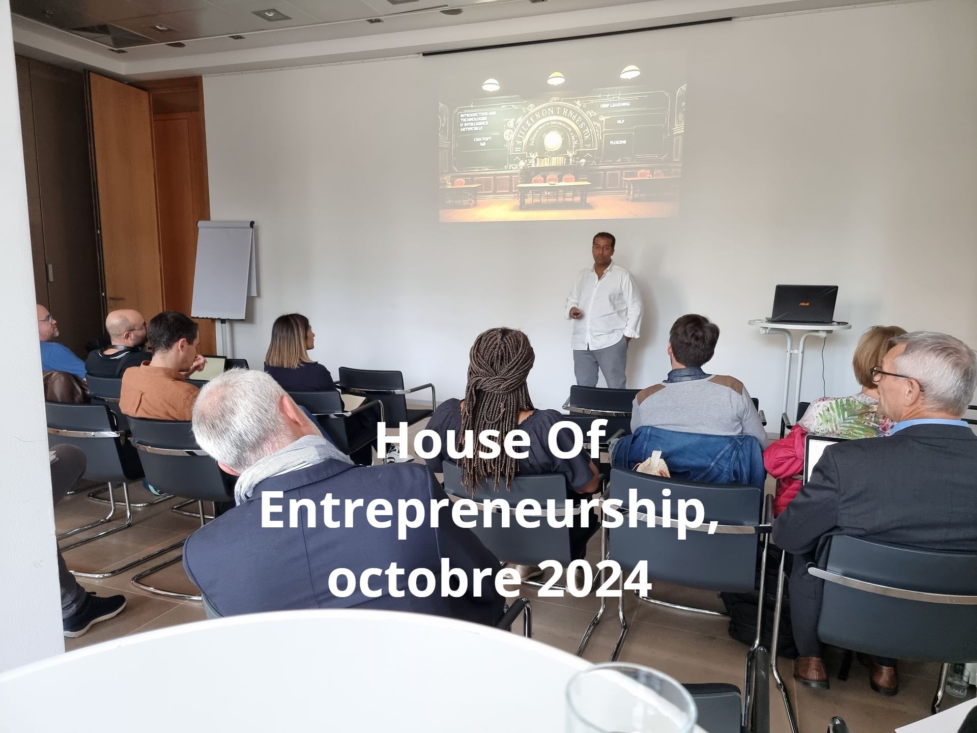 Une présentation à la Maison de l'Entrepreneuriat en octobre 2024. Un orateur se tient devant un écran et s'adresse à un public assis dans une salle de conférence.