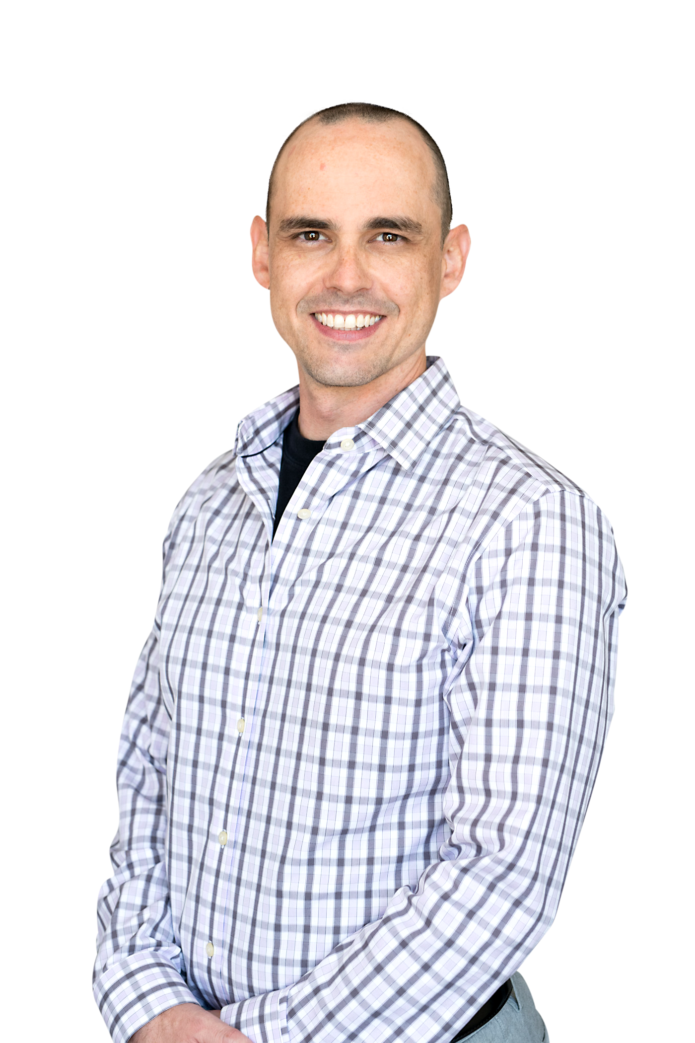 A man in a plaid shirt is smiling and standing in front of a white background.
