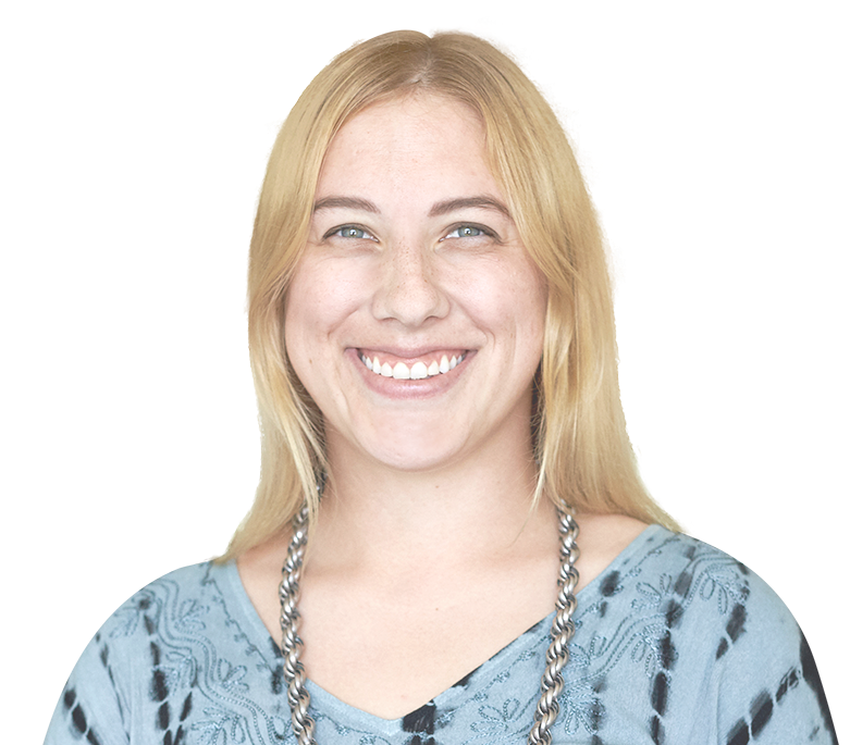 A woman wearing a tie dye shirt and a necklace smiles for the camera