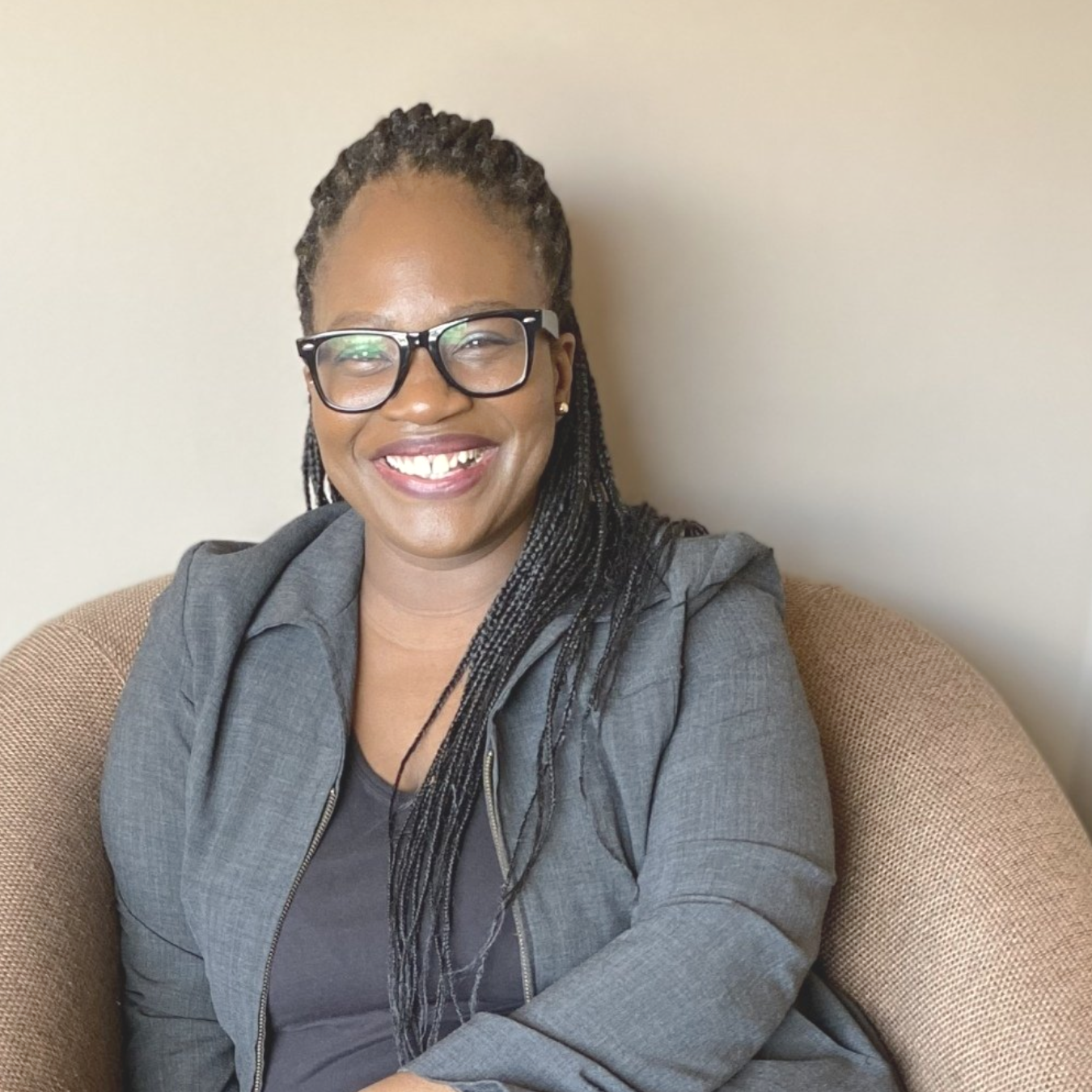 A woman is sitting in a chair with her legs crossed and smiling.