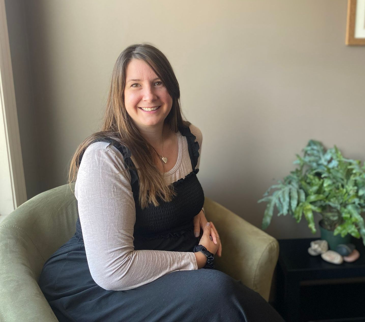 A woman is sitting in a chair and smiling for the camera.