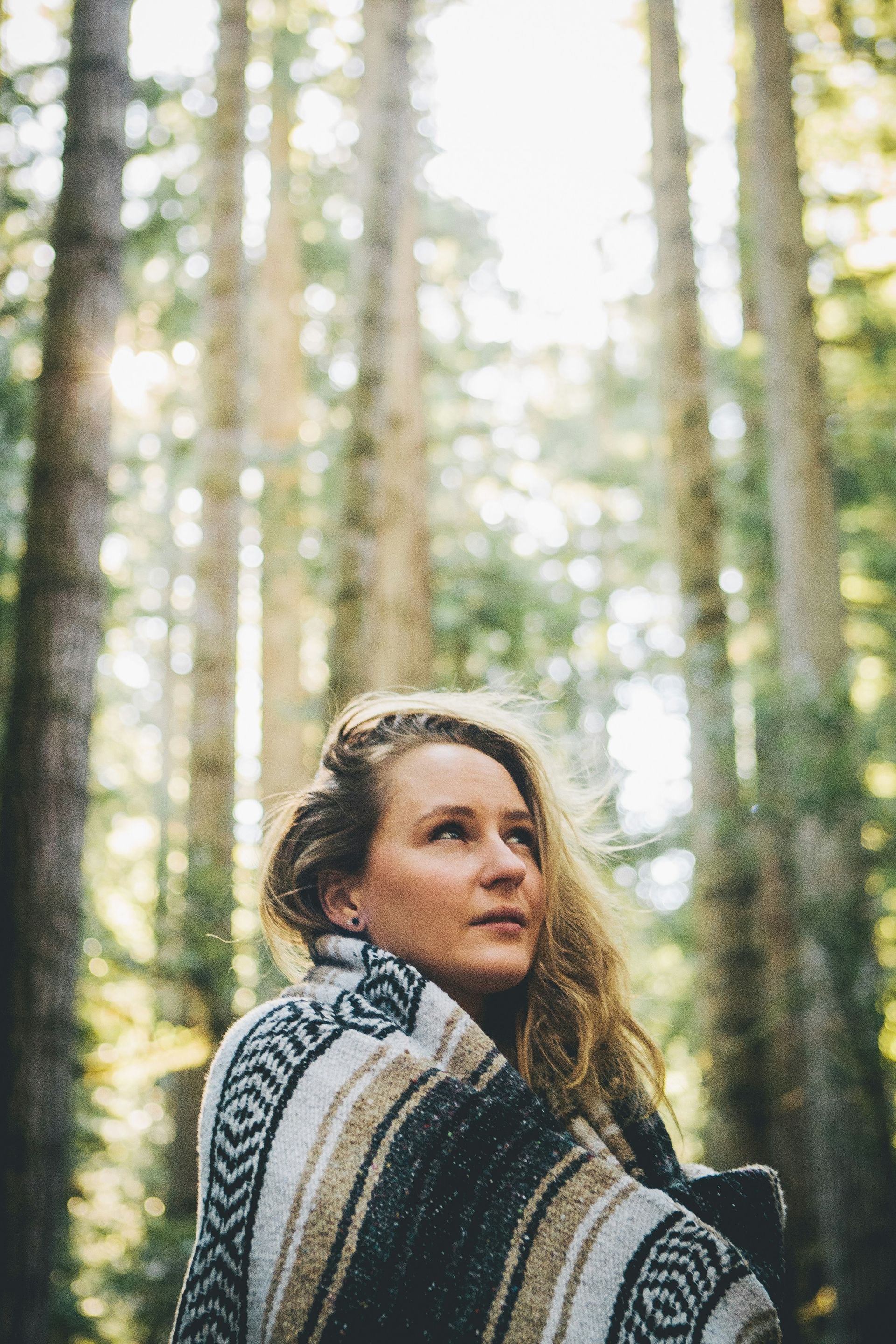 Woman in forest wrapped in blanket wondering whether she has PTSD or Complex Trauma