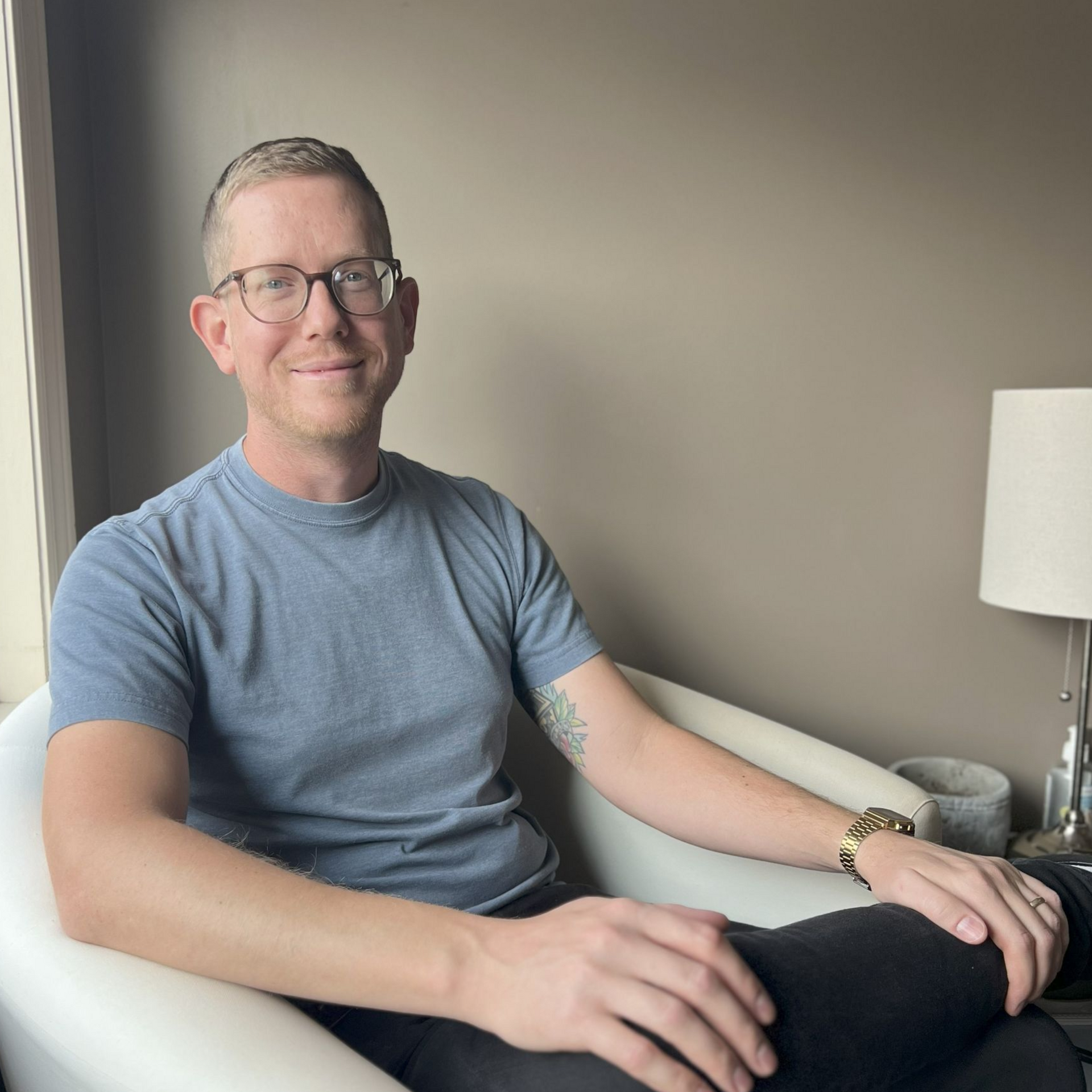 A man wearing glasses and a striped shirt is smiling for the camera.