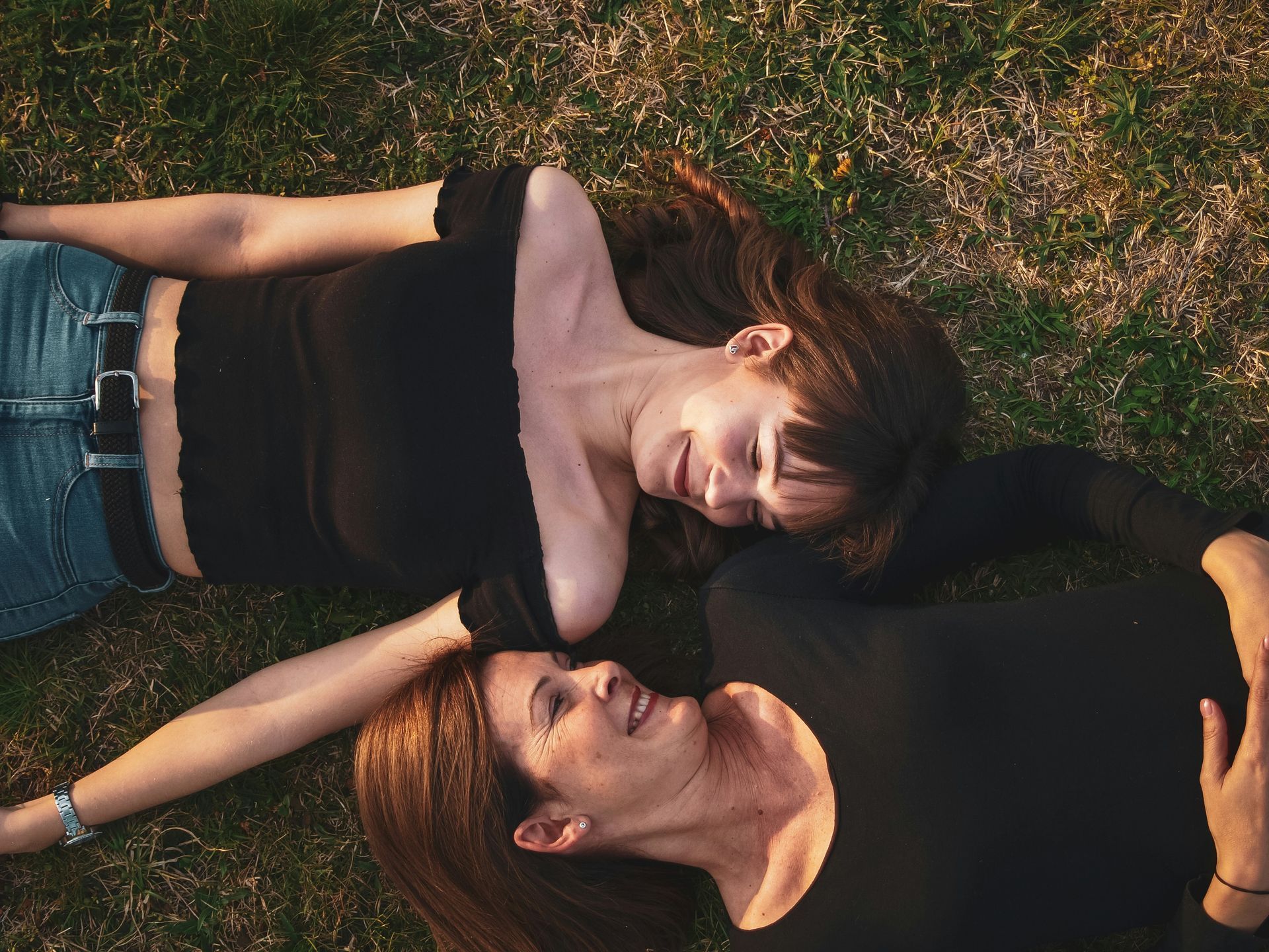 Mother and teen daughter lie on the grass talking about starting psychotherapy