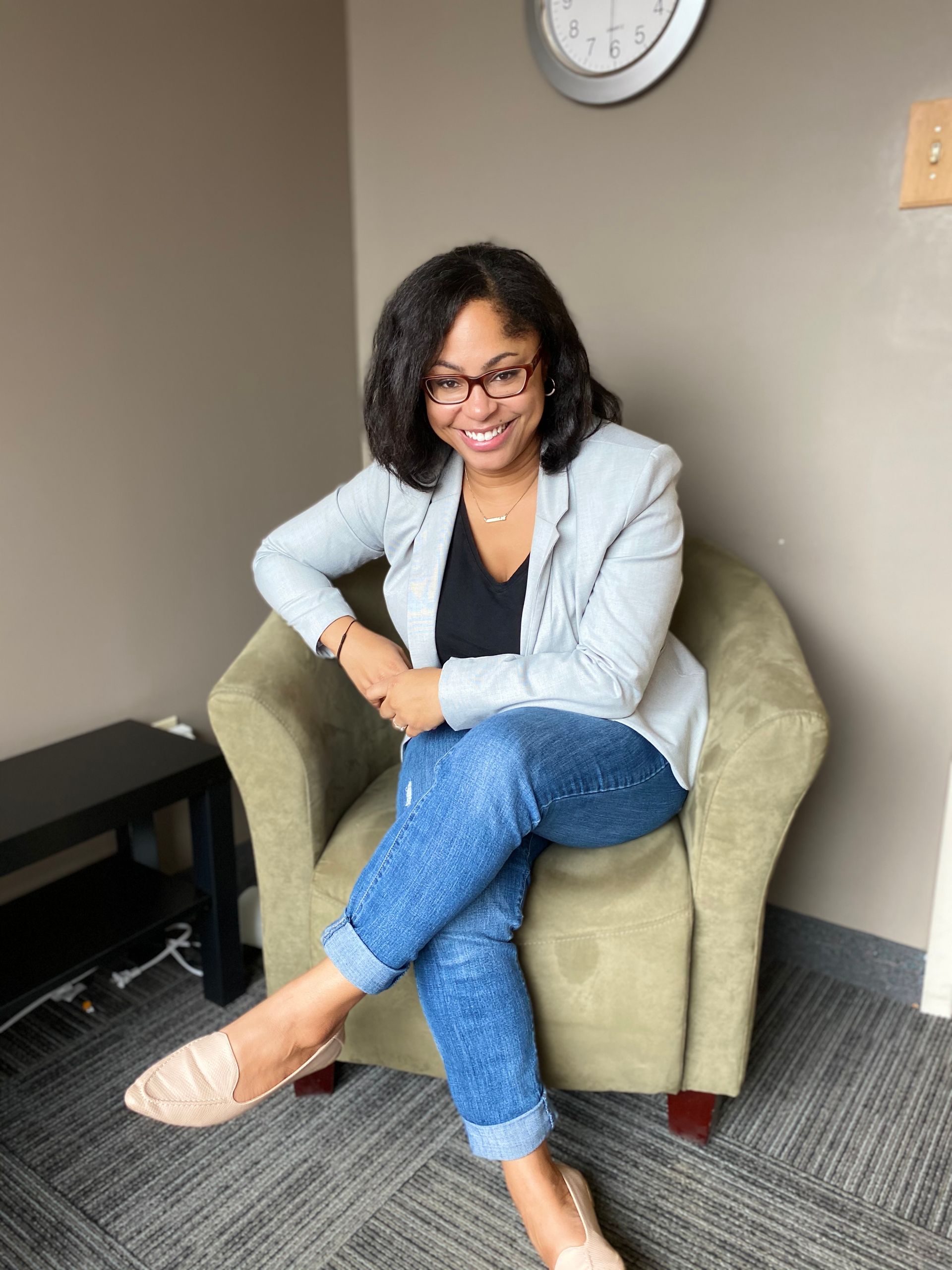 A woman is sitting in a red chair in front of a window.