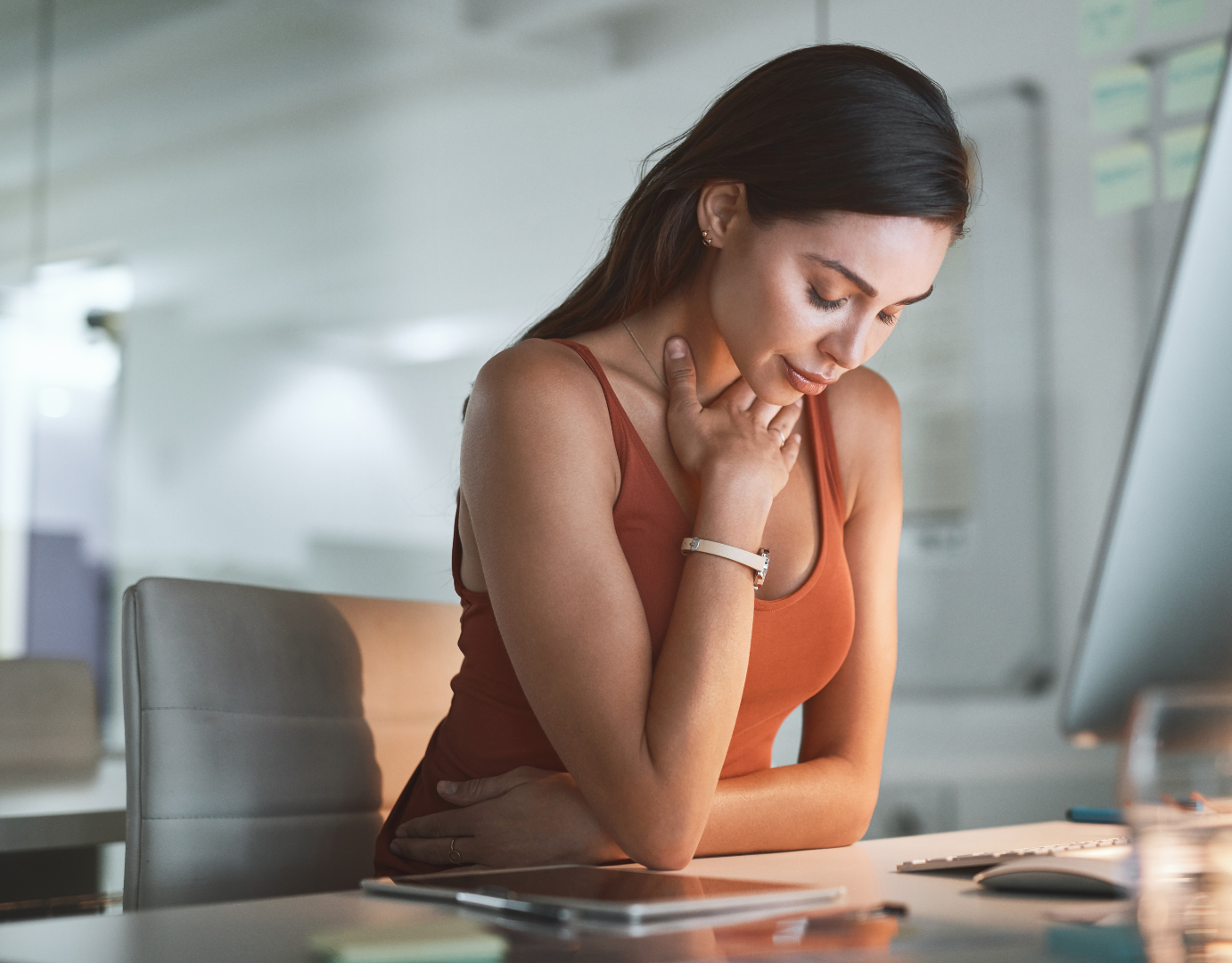 A woman is sitting at a desk looking at a computer screen.