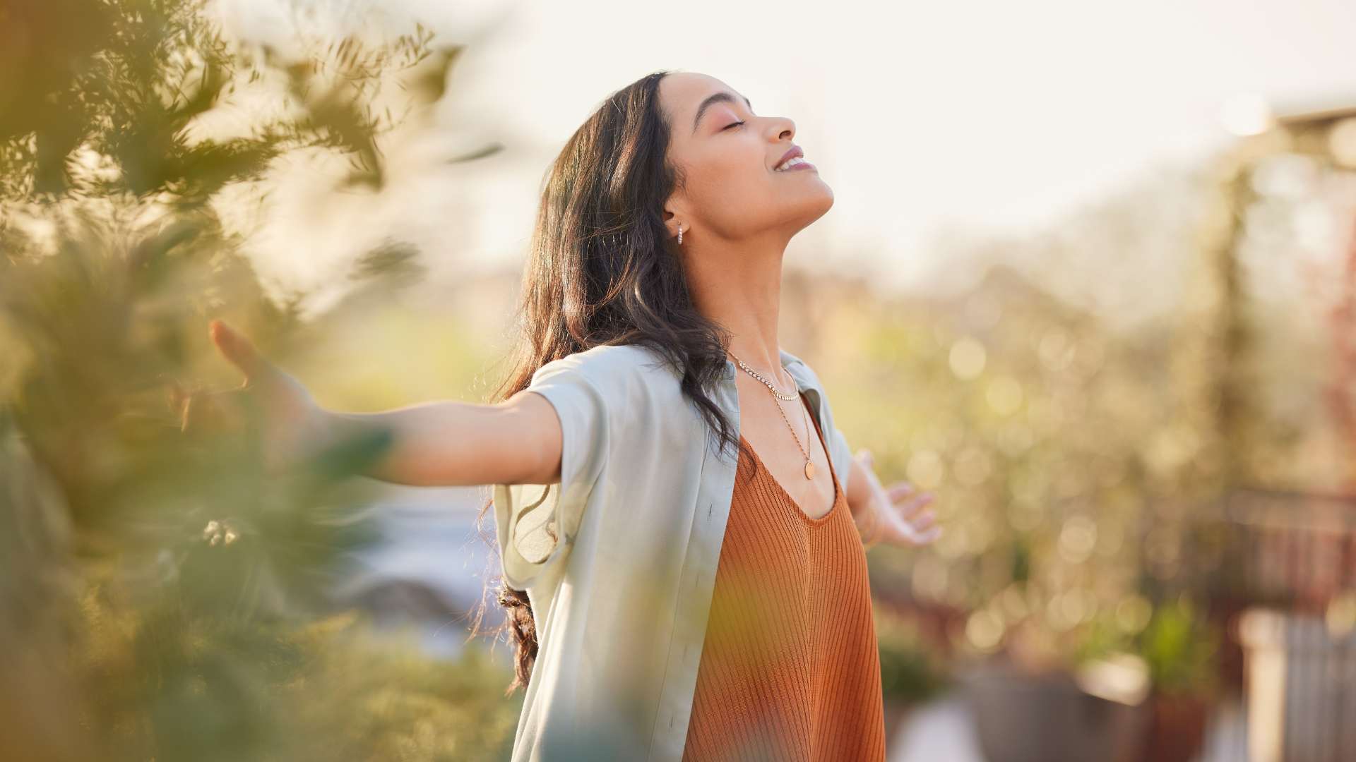 A woman is standing in a field with her arms outstretched.