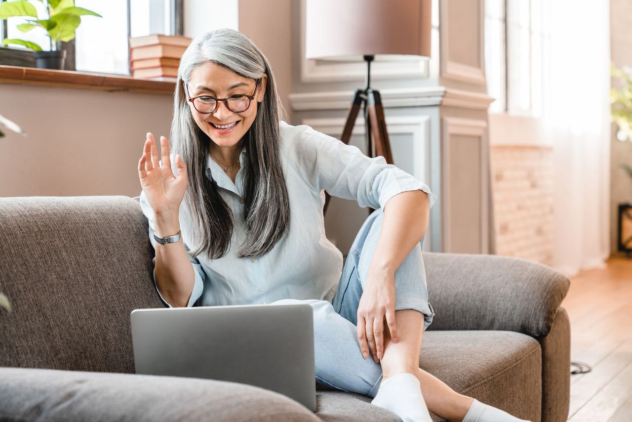 A woman is sitting on a couch using a laptop computer.