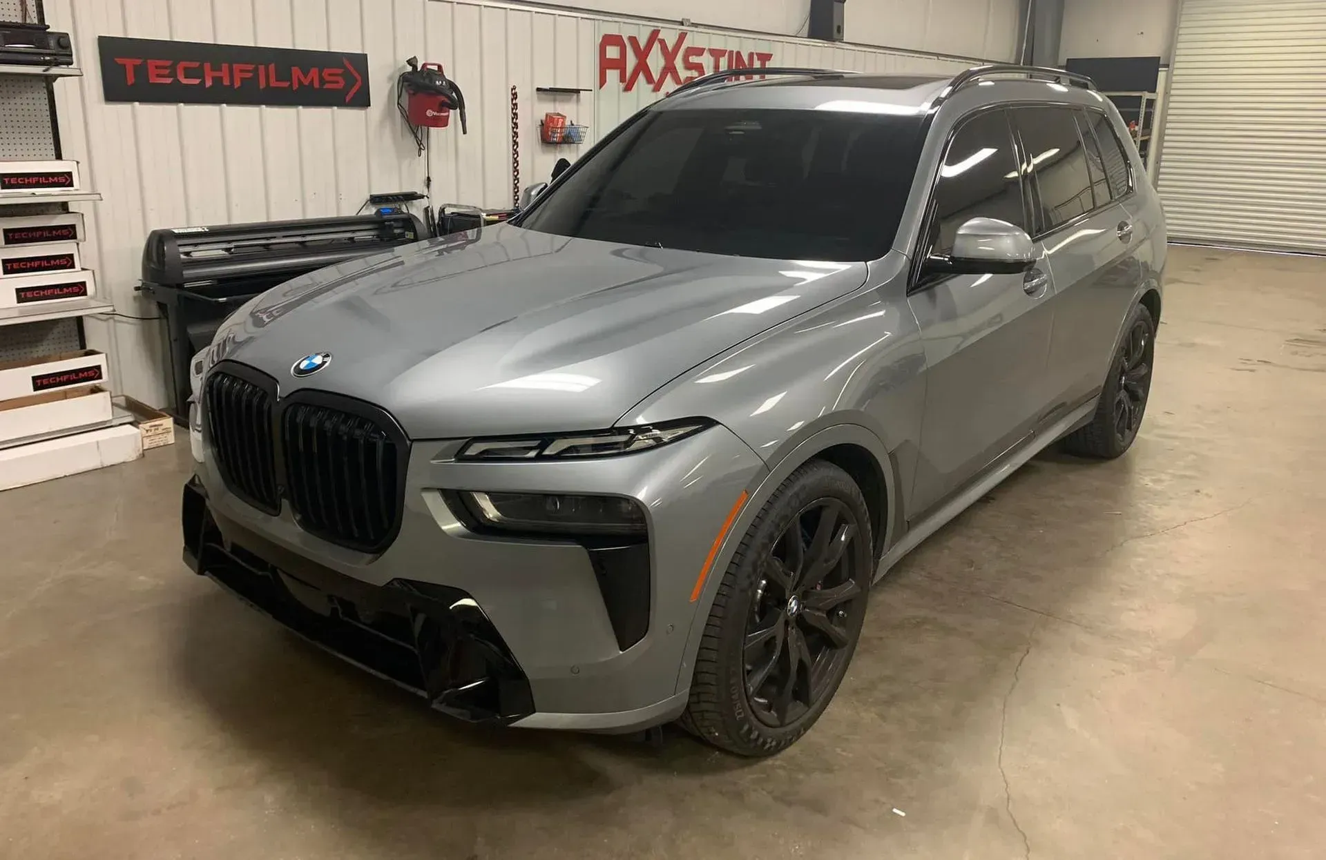 A gray bmw x7 m is parked in a garage.