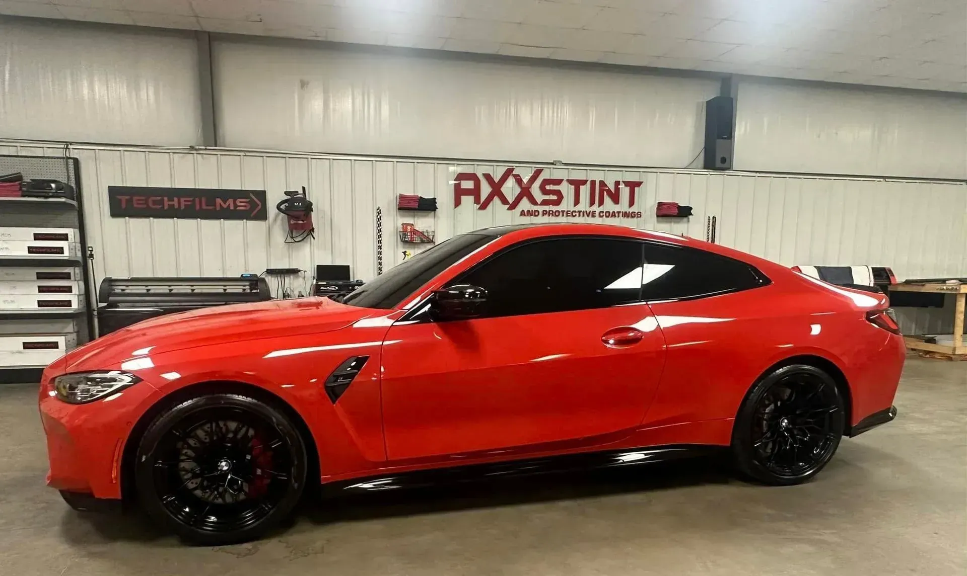 A red bmw m4 is parked in a garage.
