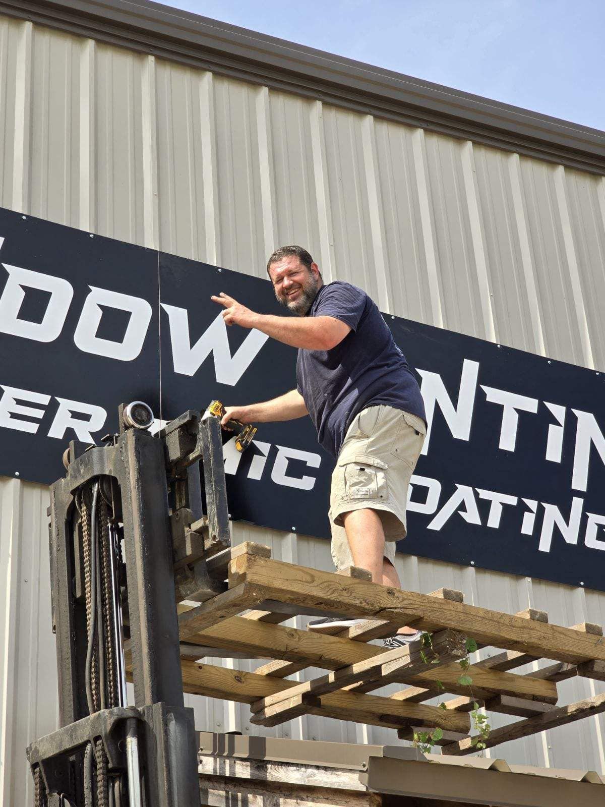 A man is standing on a wooden pallet in front of a sign that says dow coatings