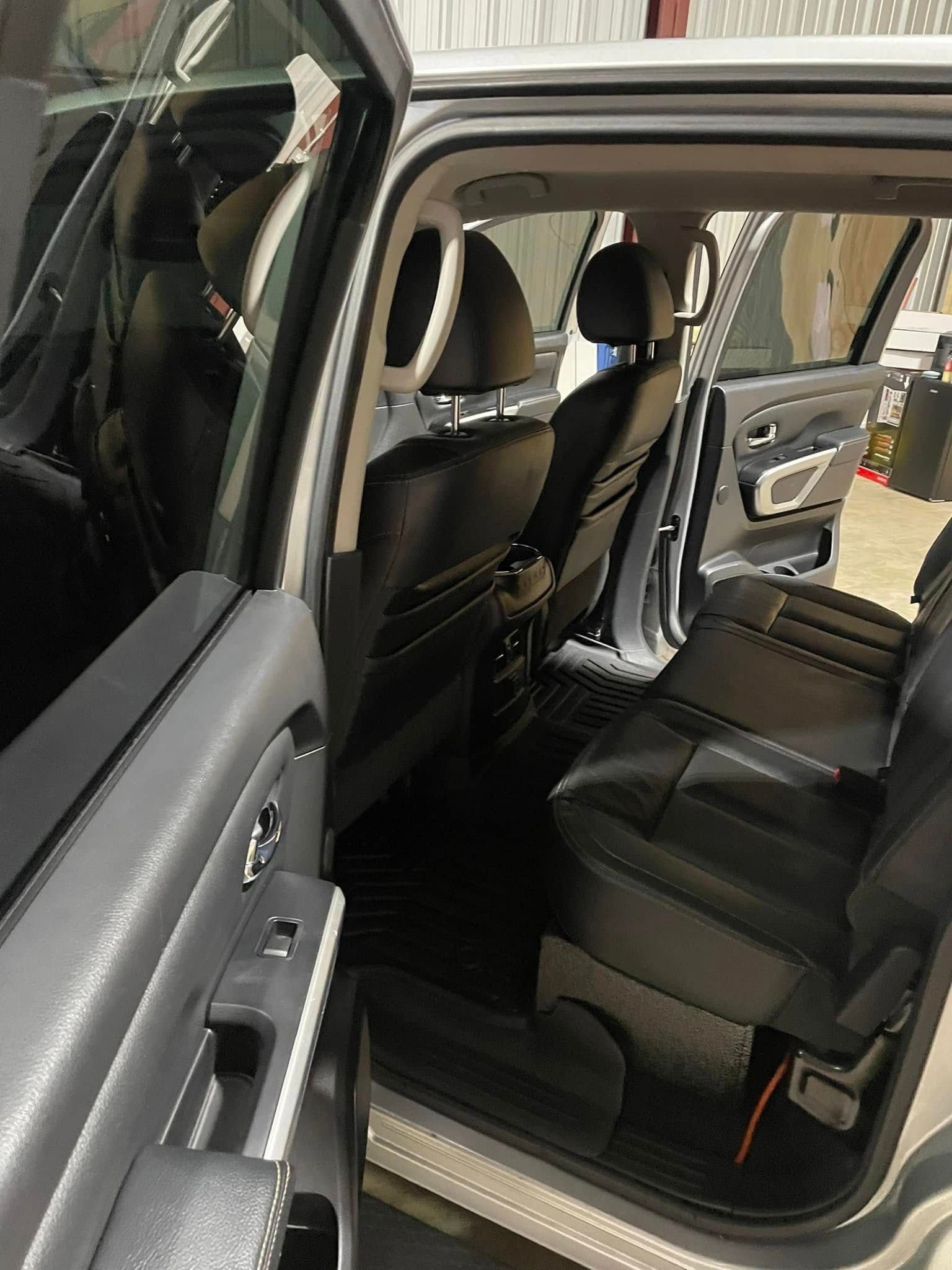 The inside of a car with the door open and the seats folded down.
