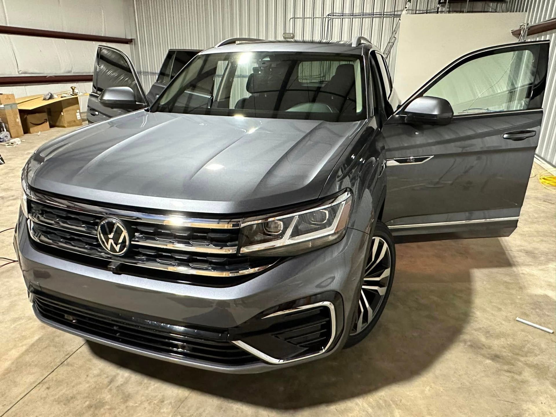 A volkswagen atlas is parked in a garage with its doors open.