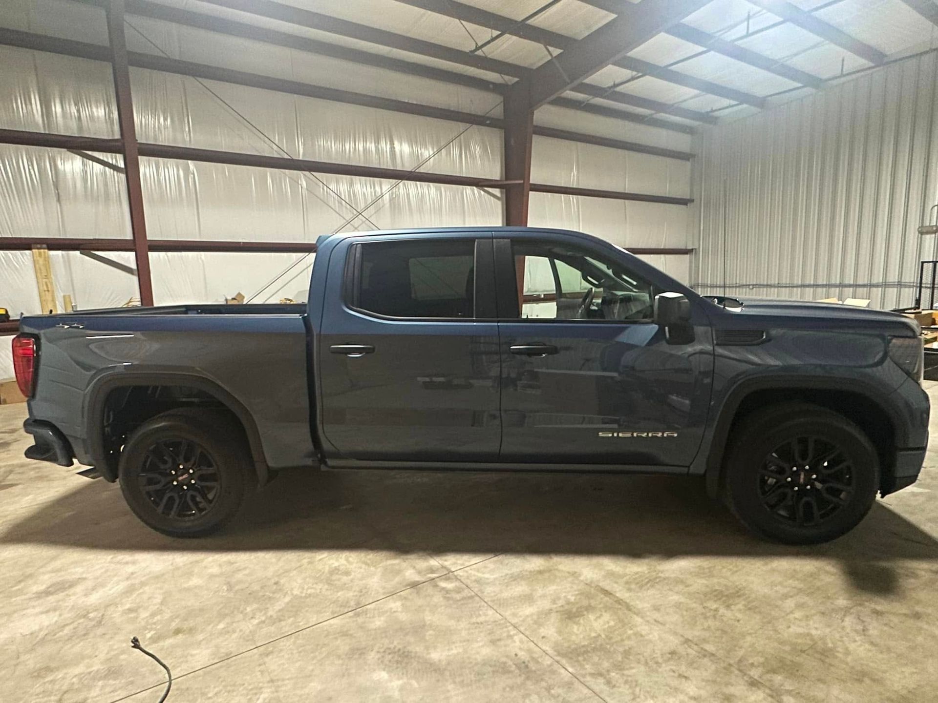 A blue pickup truck is parked in a garage.