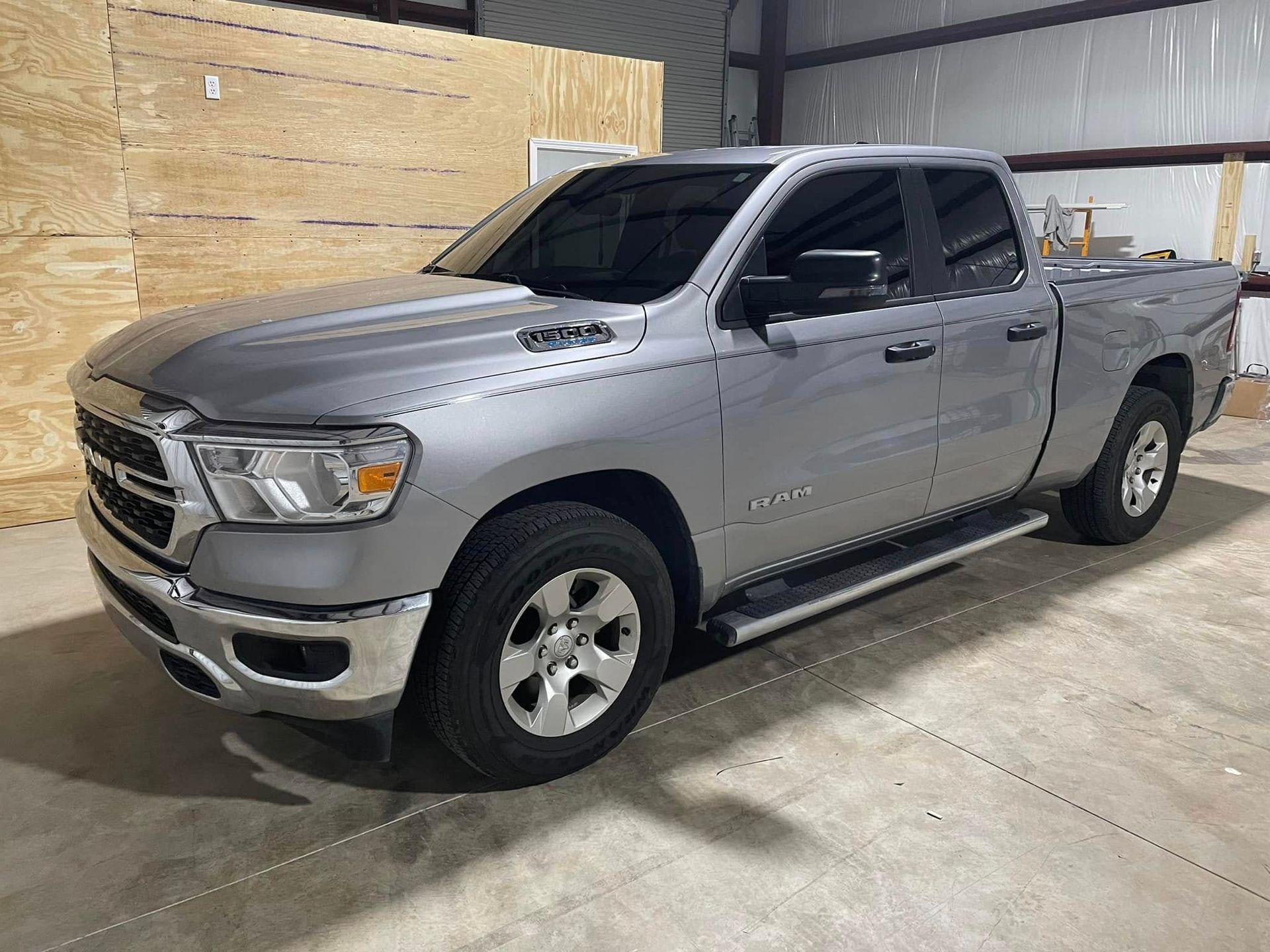 A silver ram 1500 truck is parked in a garage.