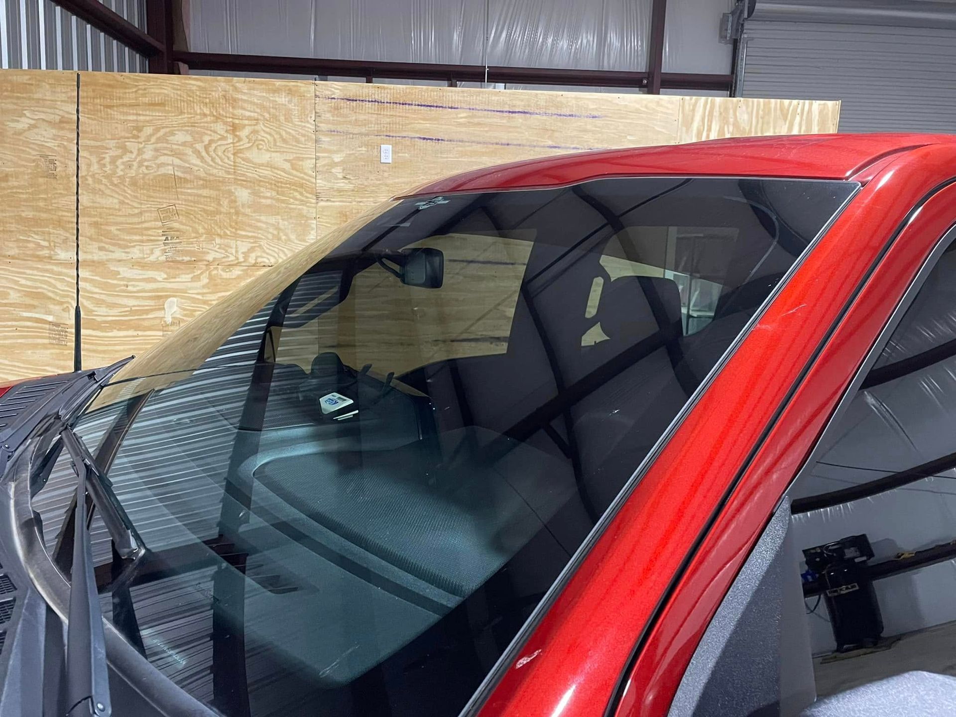 A red truck with a broken windshield is sitting in a garage.