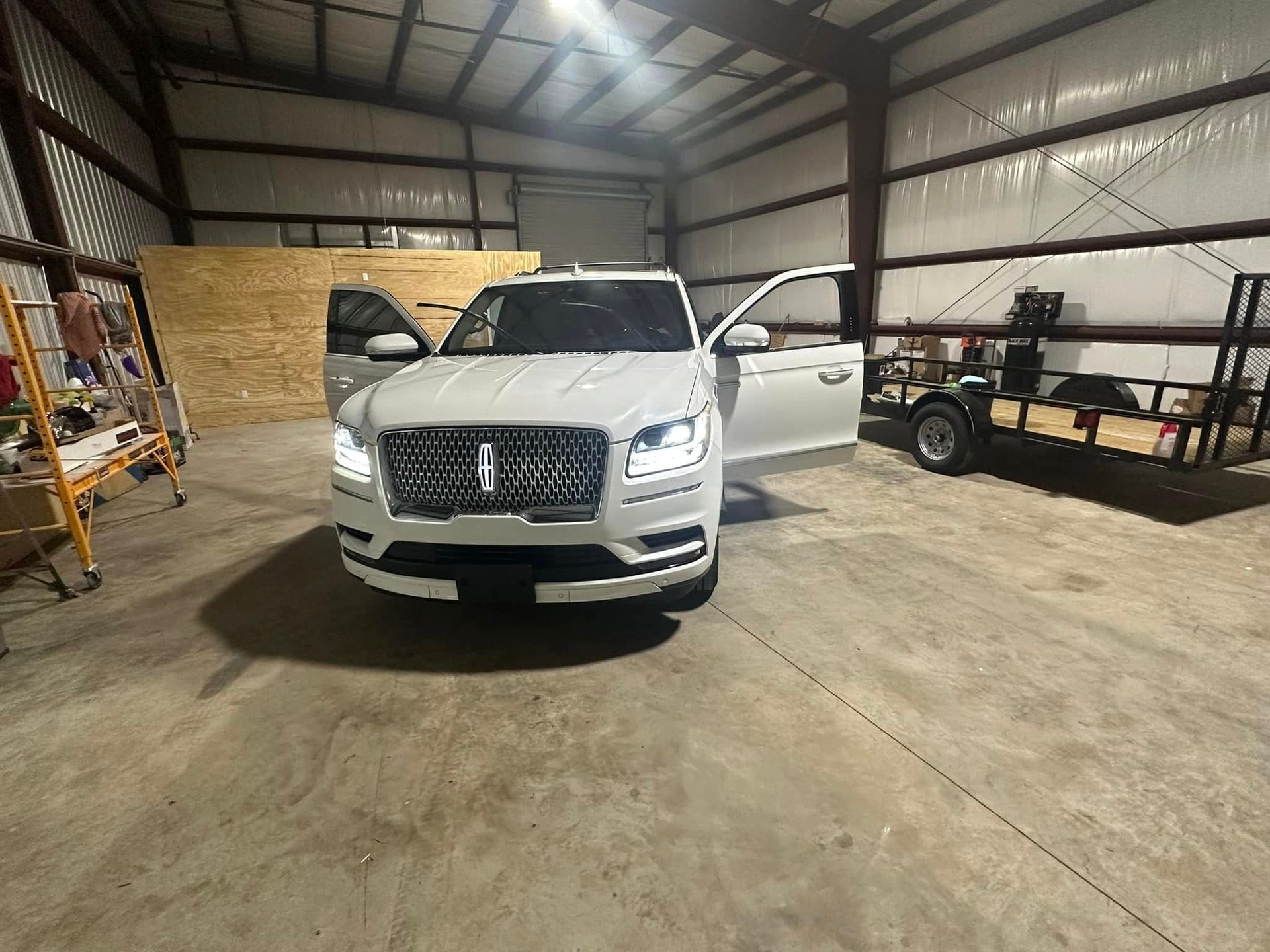 A white car is parked in a garage with its doors open.