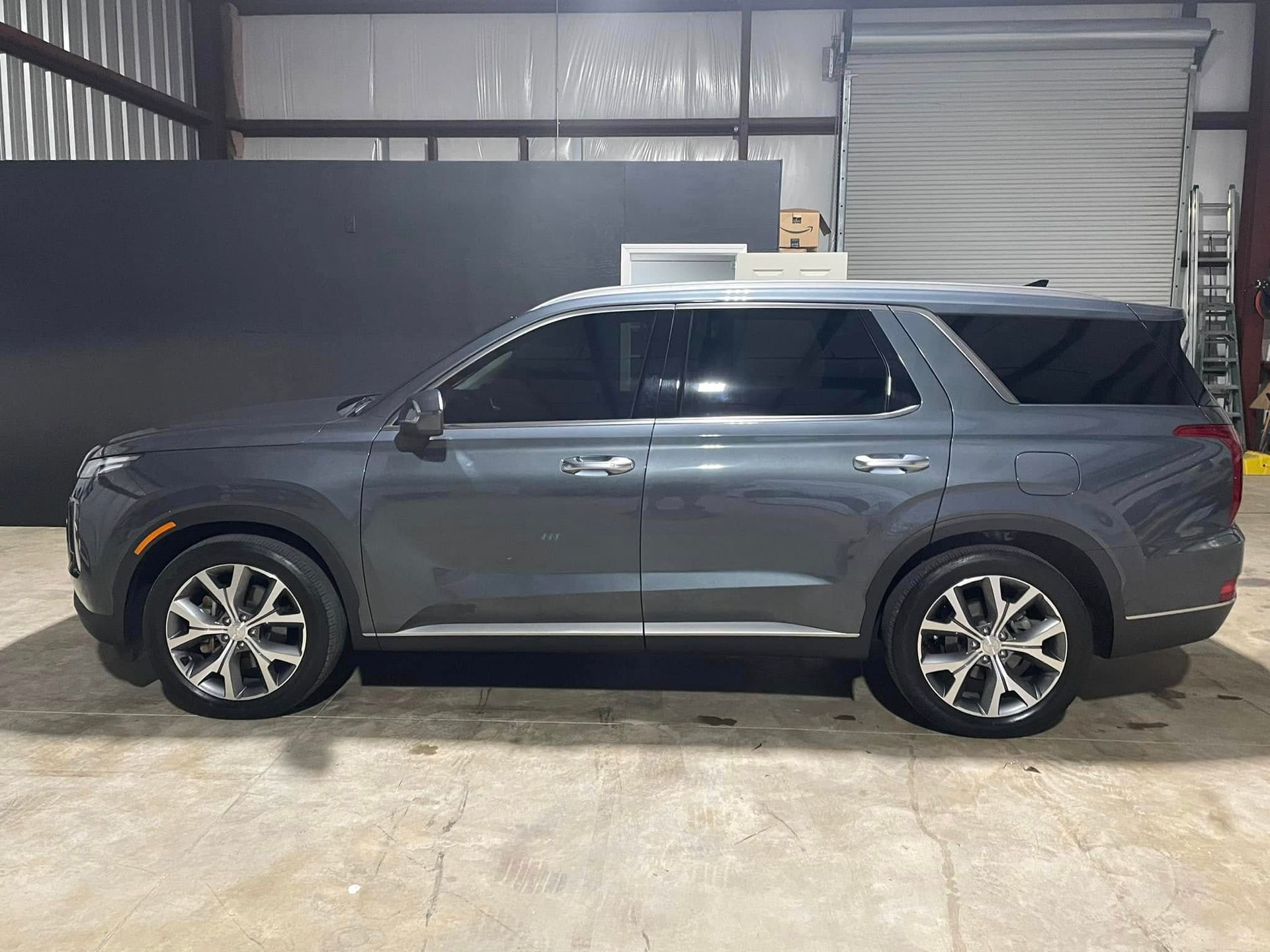 A gray hyundai palisade is parked in a garage.