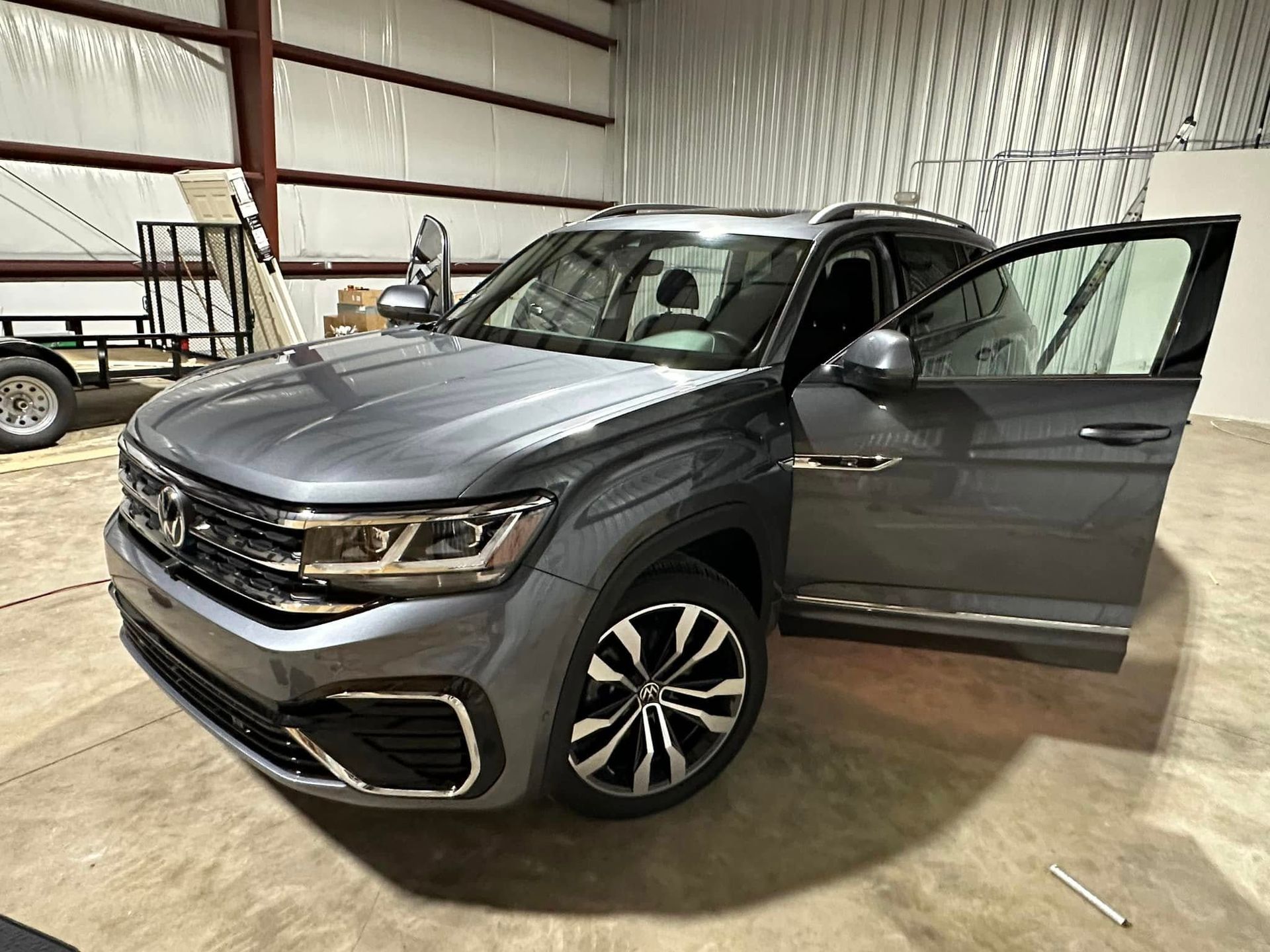 A volkswagen atlas crosstrek is parked in a garage with its doors open.