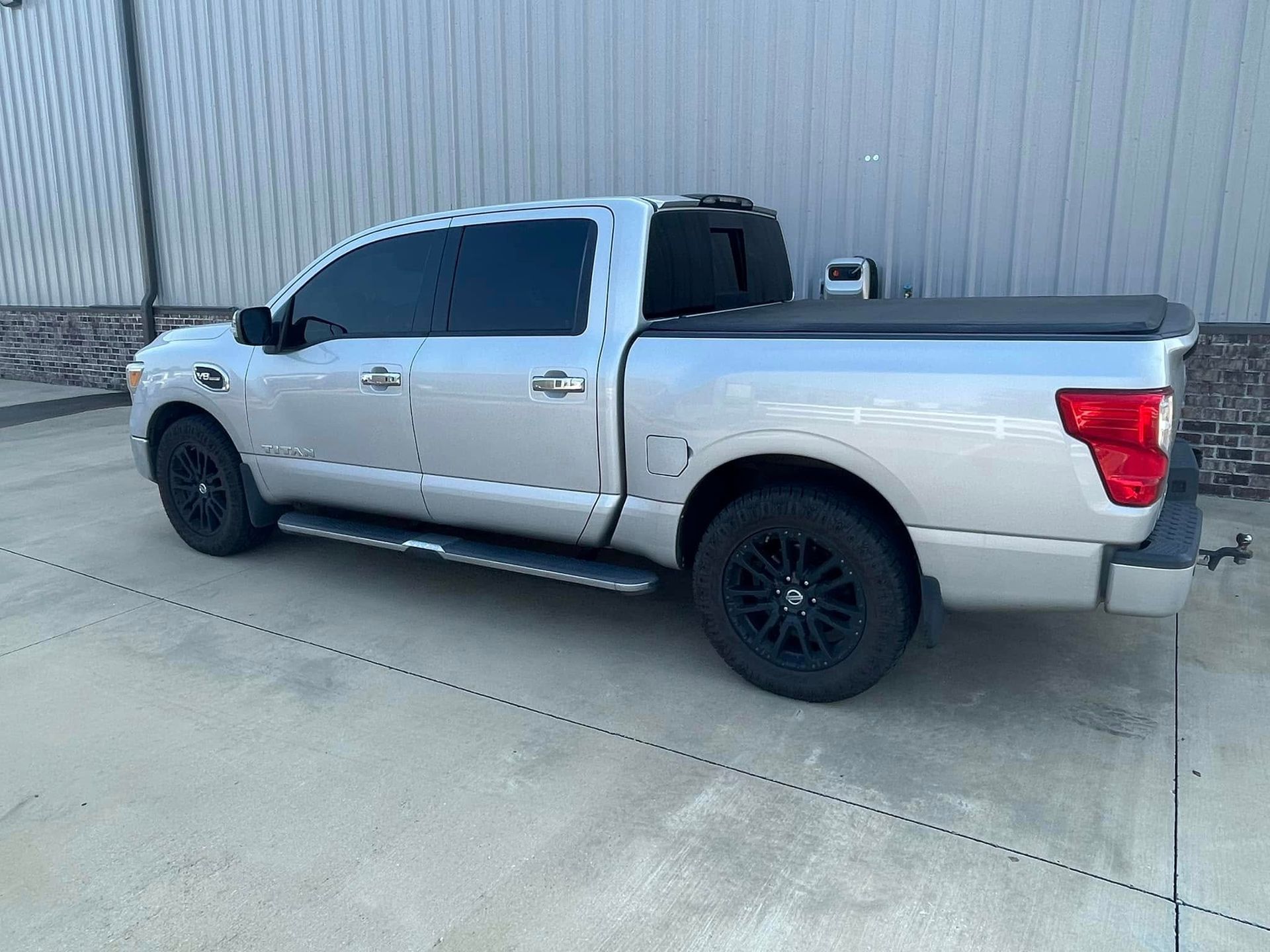 A silver truck is parked in a parking lot in front of a building.