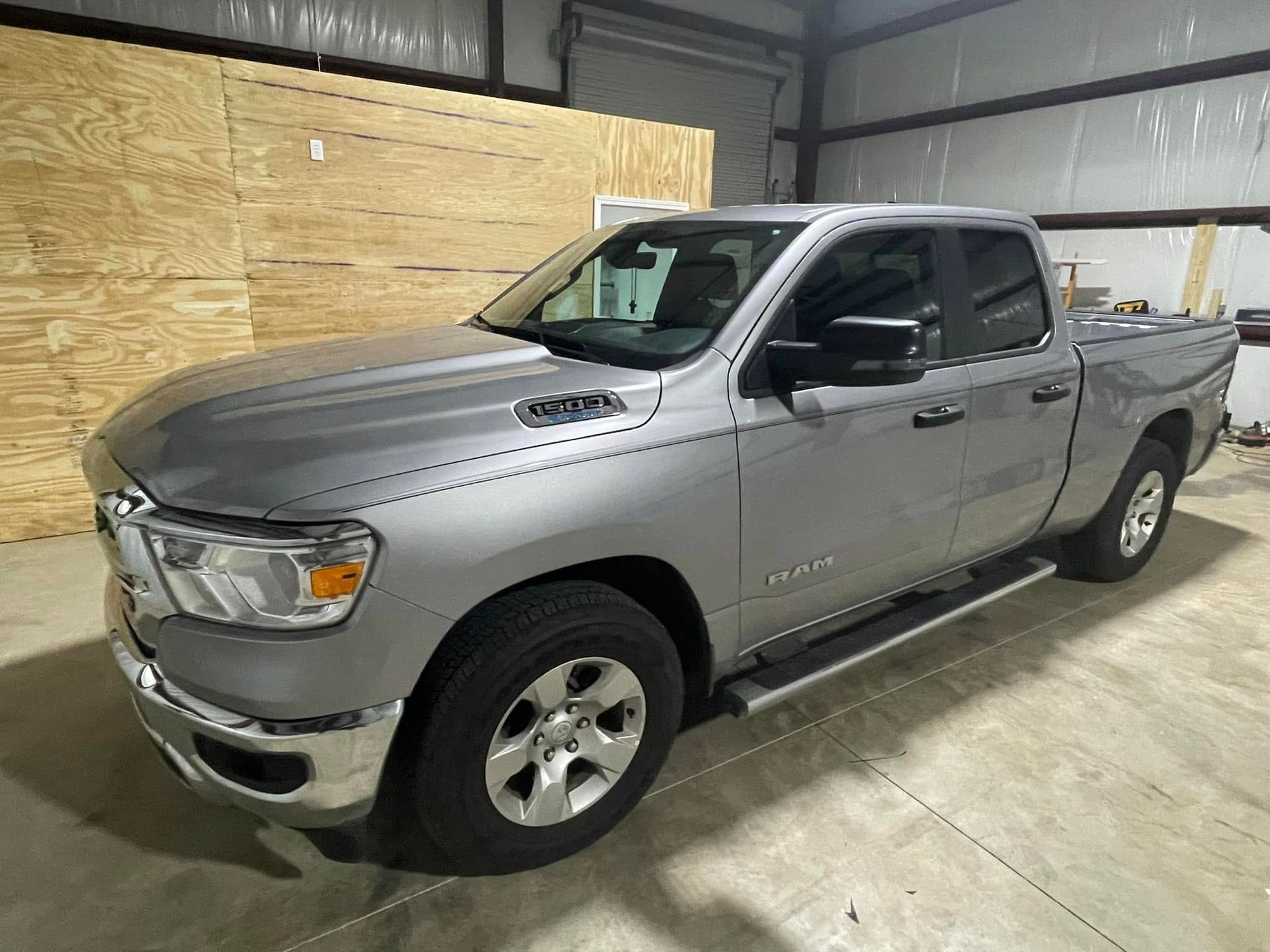 A silver ram 1500 truck is parked in a garage.