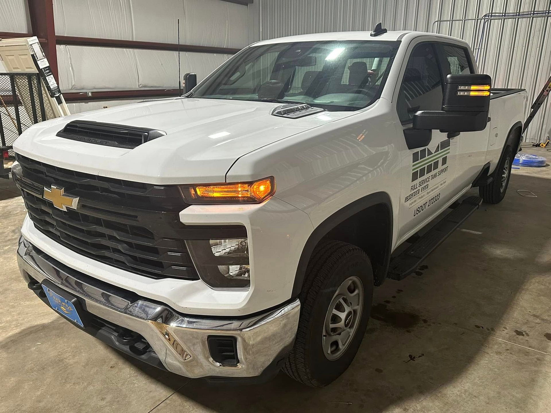 A white truck is parked in a garage next to a wall.
