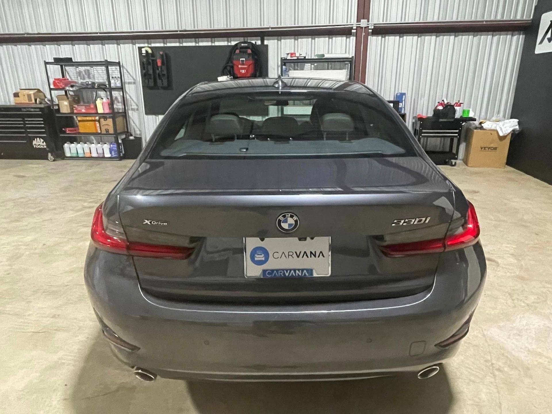 A gray bmw 3 series is parked in a garage.