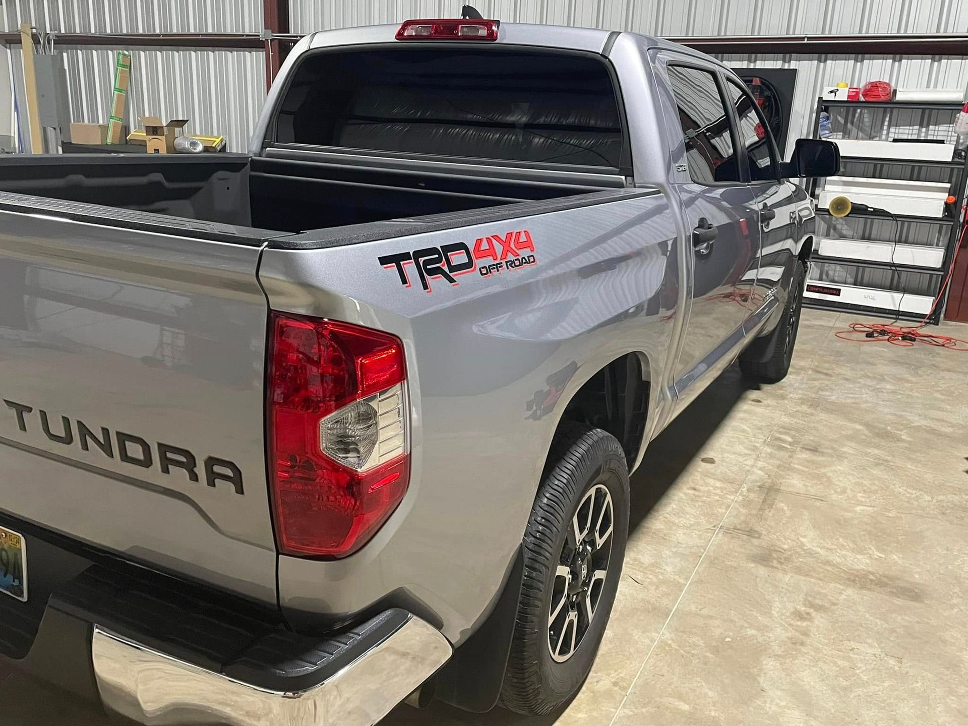A silver toyota tundra truck is parked in front of a building.