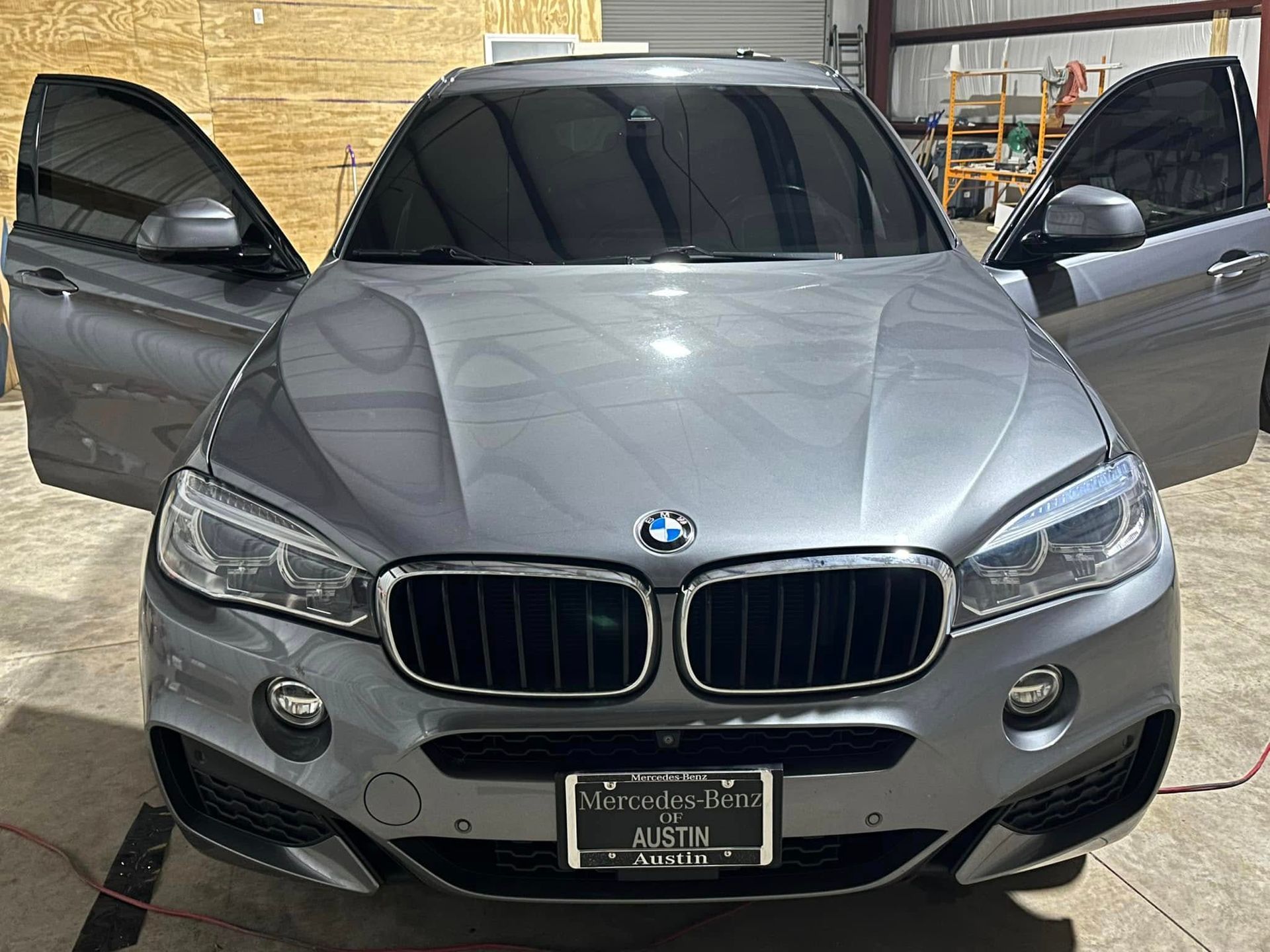 A bmw x6 is parked in a garage with its doors open.