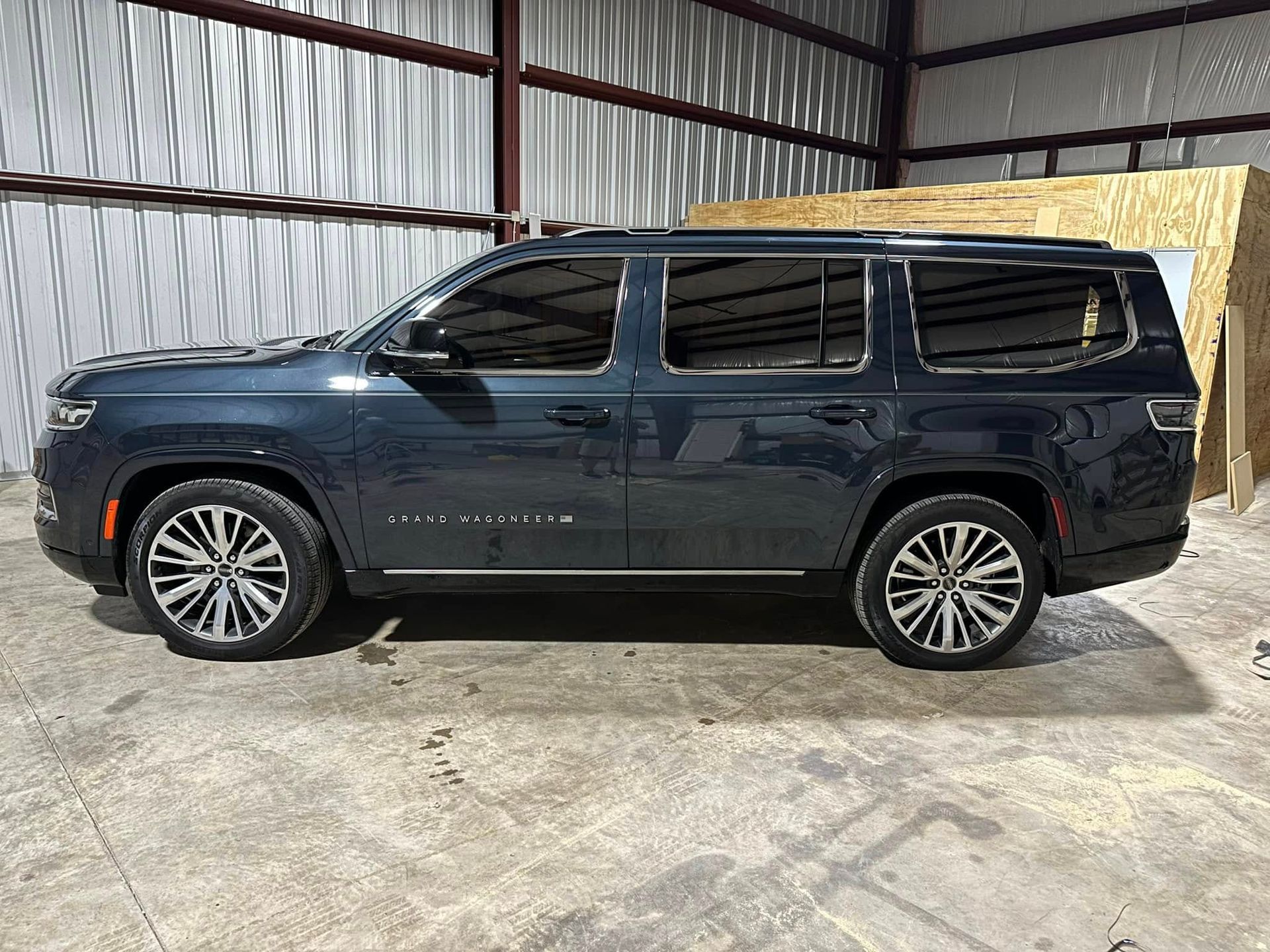 A blue jeep grand wagoneer is parked in a warehouse.