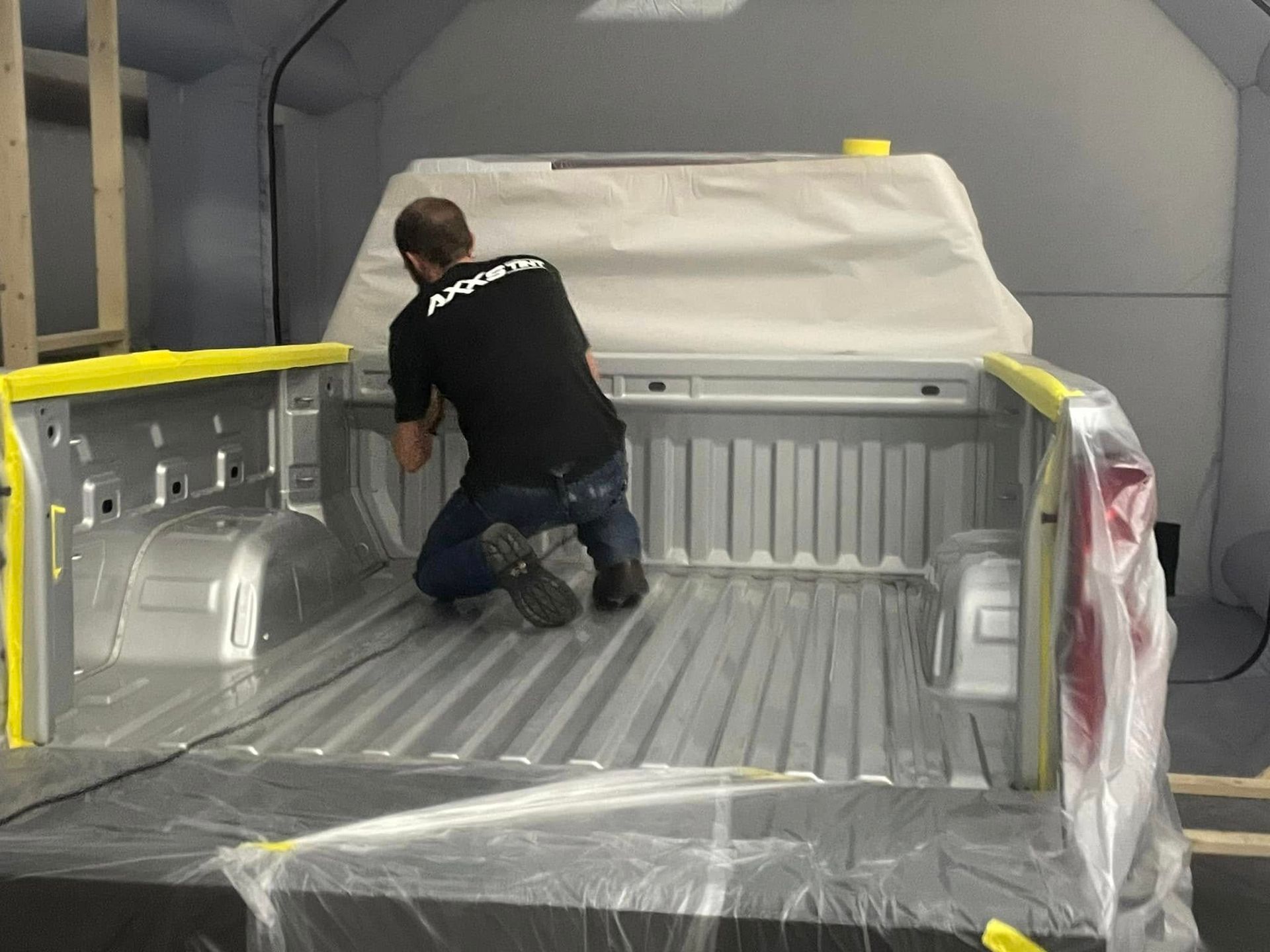 A man is kneeling in the bed of a truck.