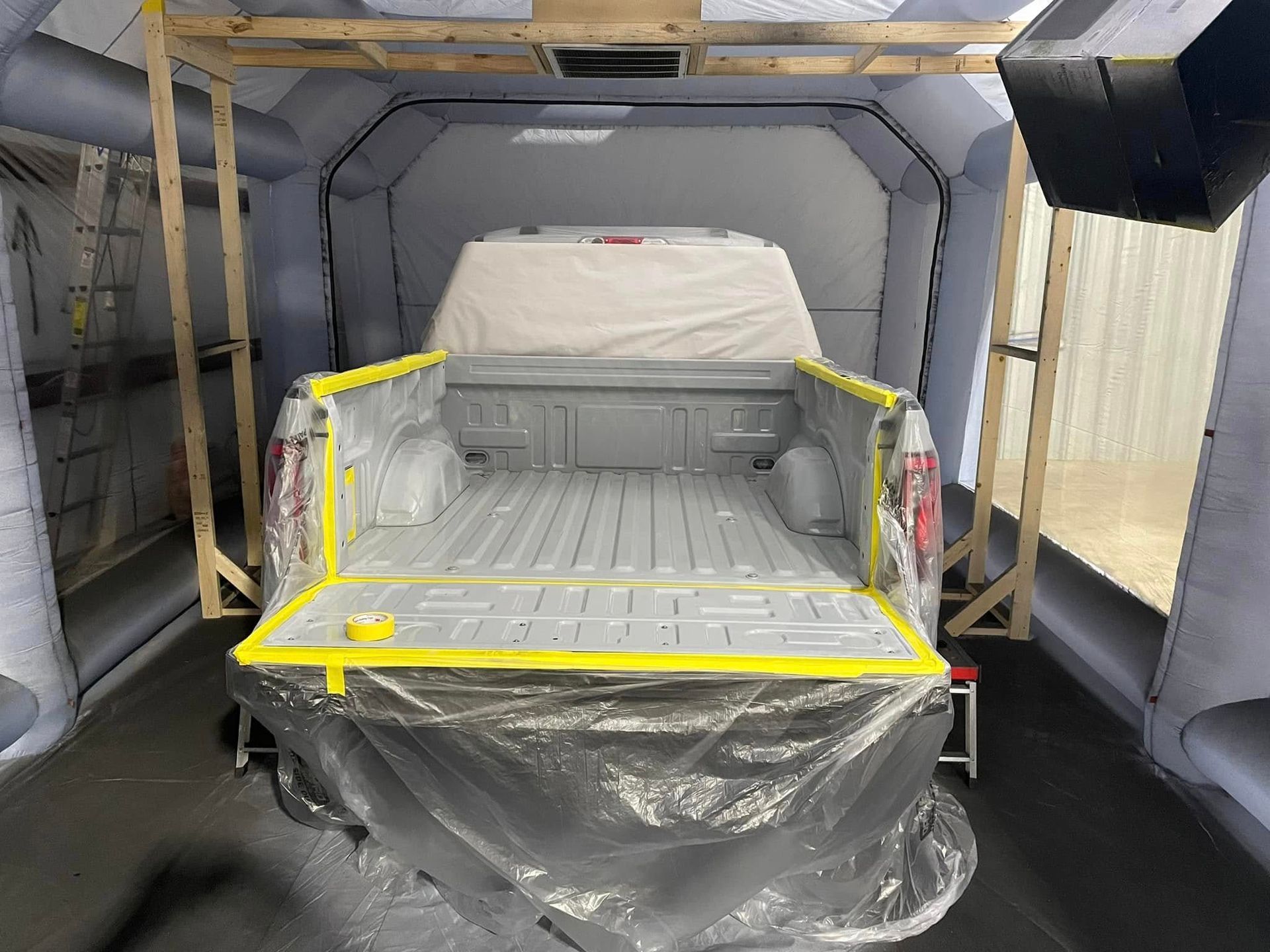 A truck is being painted in a paint booth.