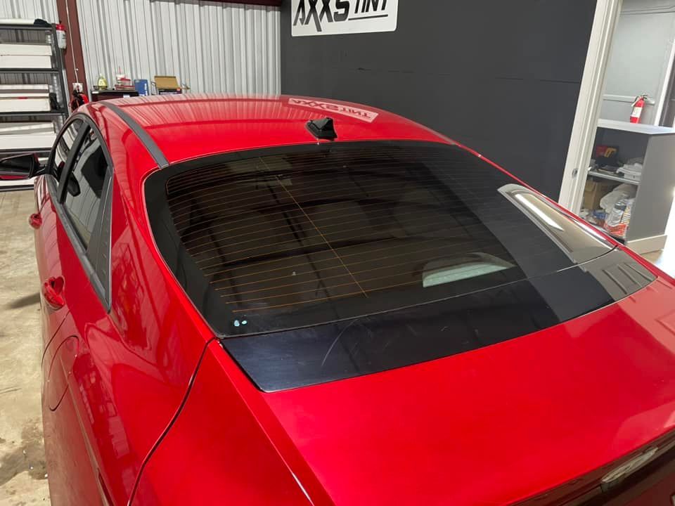 A red car is parked in a garage in front of a building.